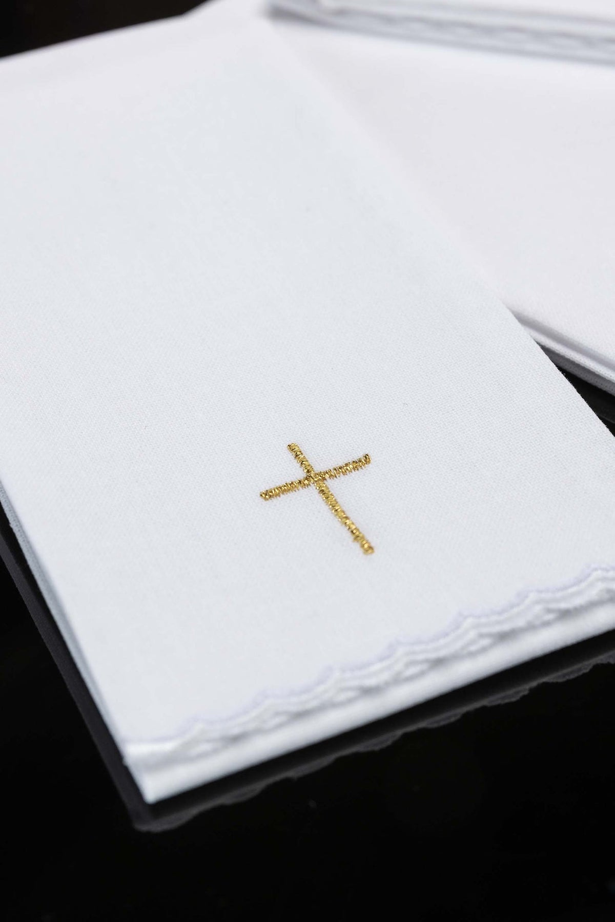 Liturgical purificator close-up with gold cross embroidery and scalloped edge