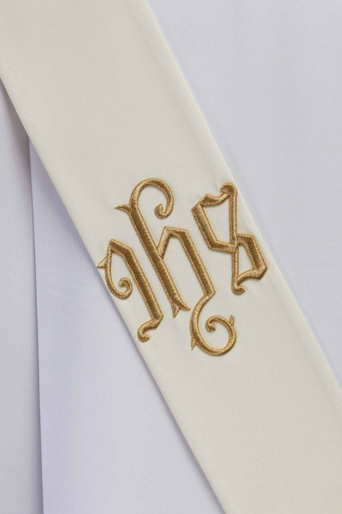IHS deacon stole close-up showing gold embroidered IHS monogram on ivory fabric