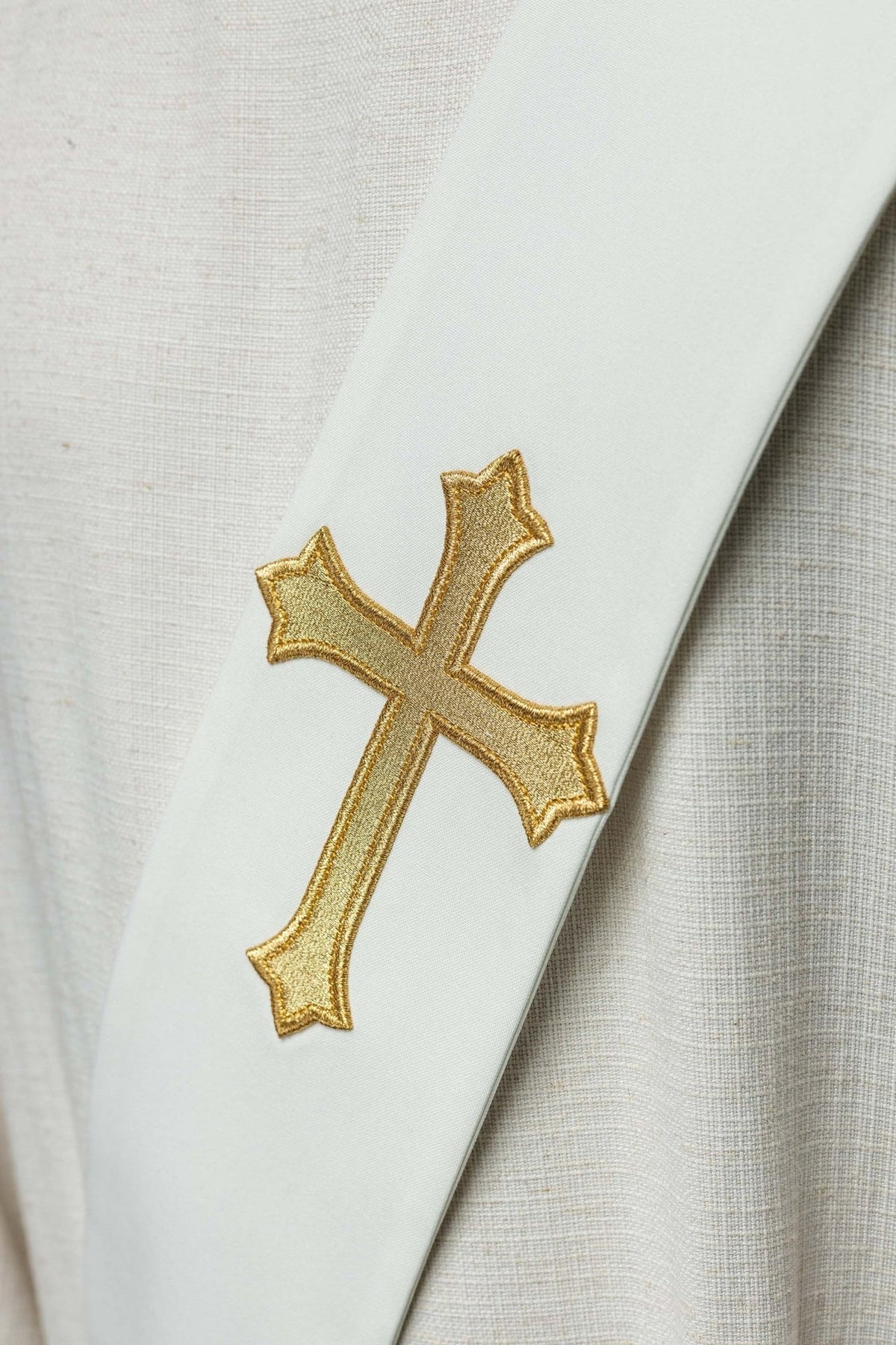 White stole close-up showing the gold embroidered cross