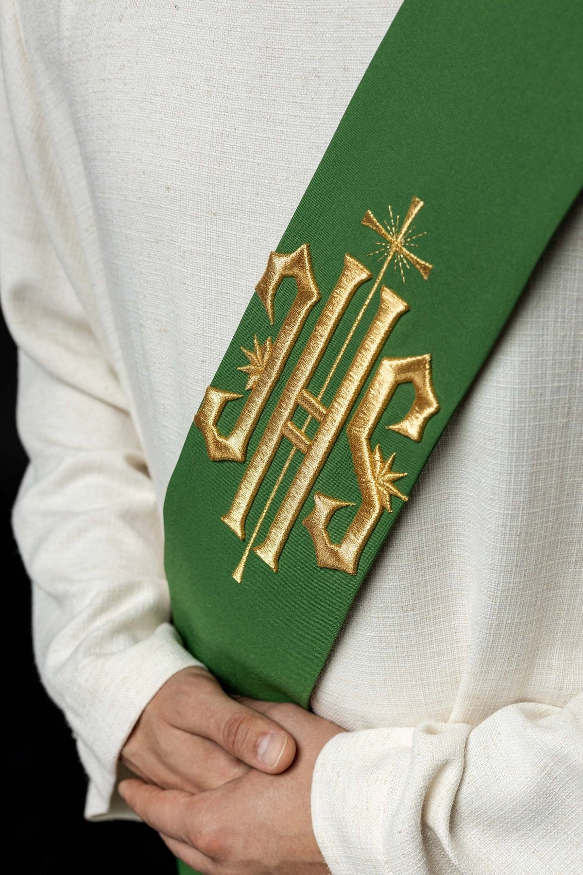 Green stole close-up showing gold embroidered IHS and cross