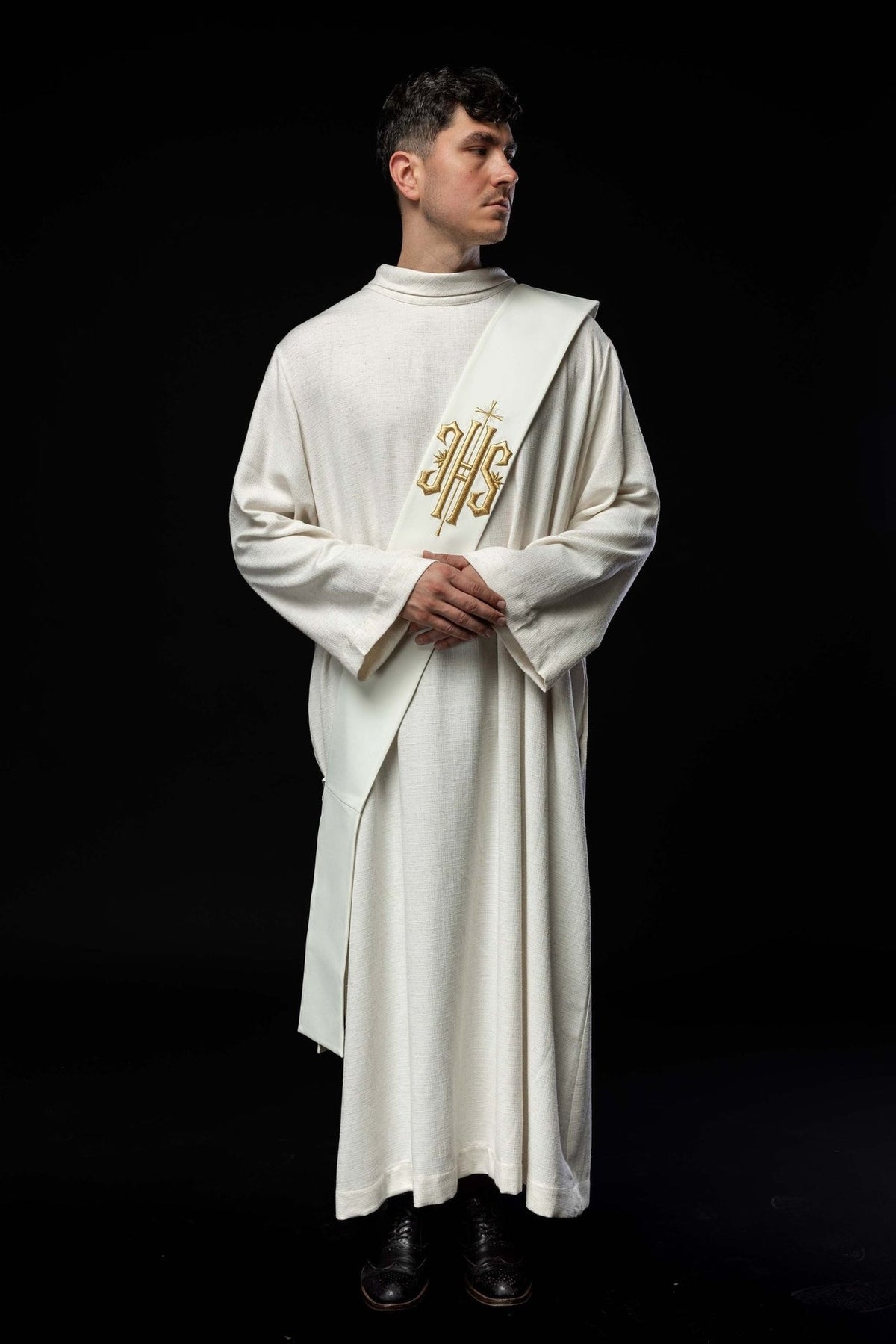 White deacon stole worn from the front, showing gold embroidered IHS and cross