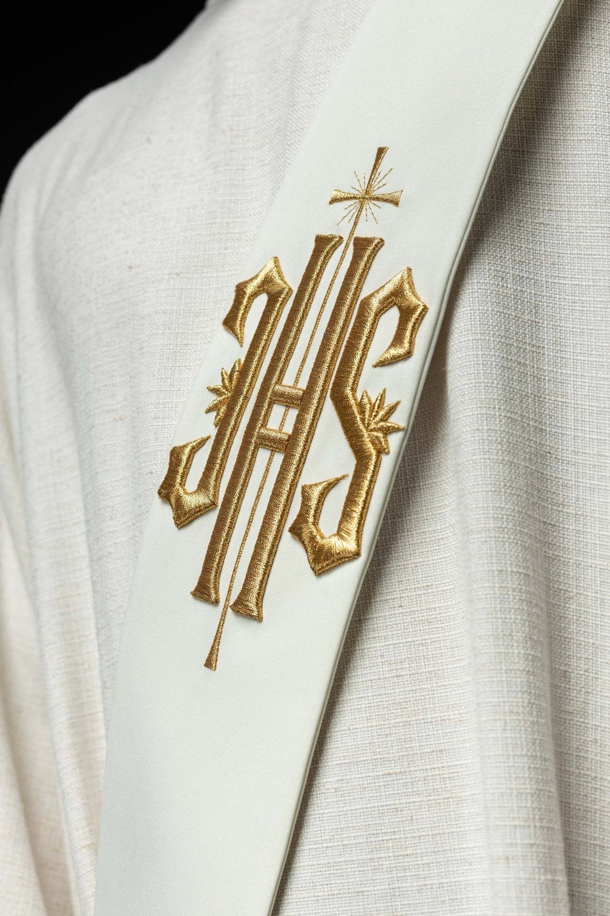 Close-up of white stole with gold embroidered IHS and small cross