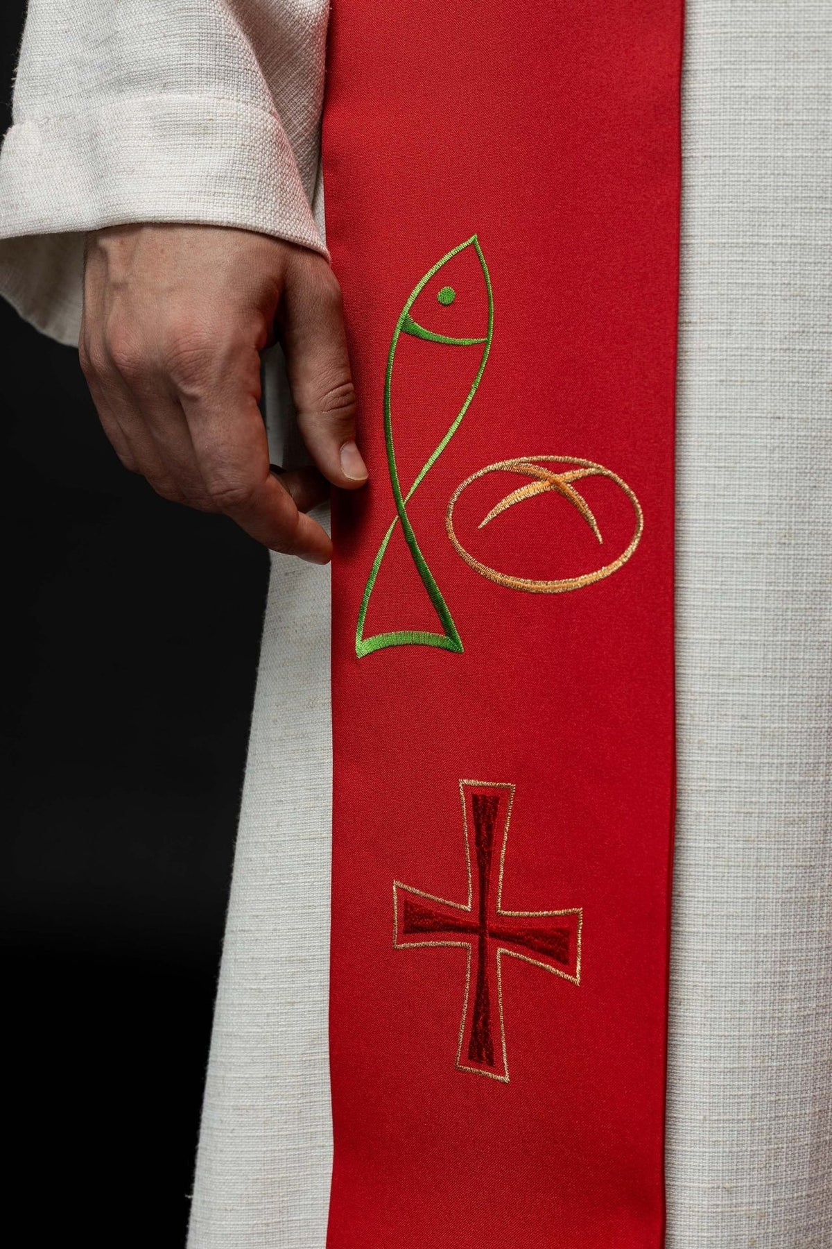 Red priest stole close-up with embroidered fish, bread and cross motifs