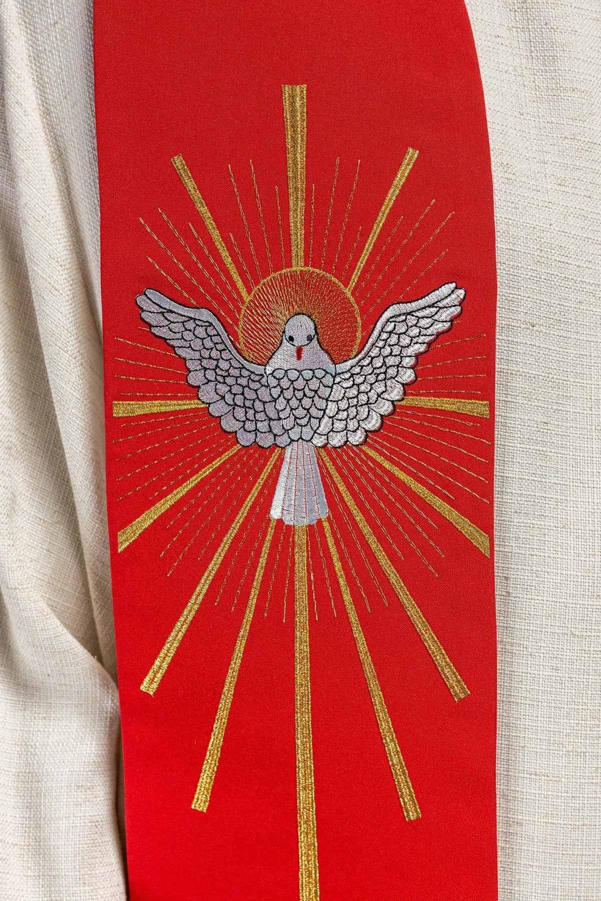 Red stole close-up showing the embroidered Holy Spirit with gold rays