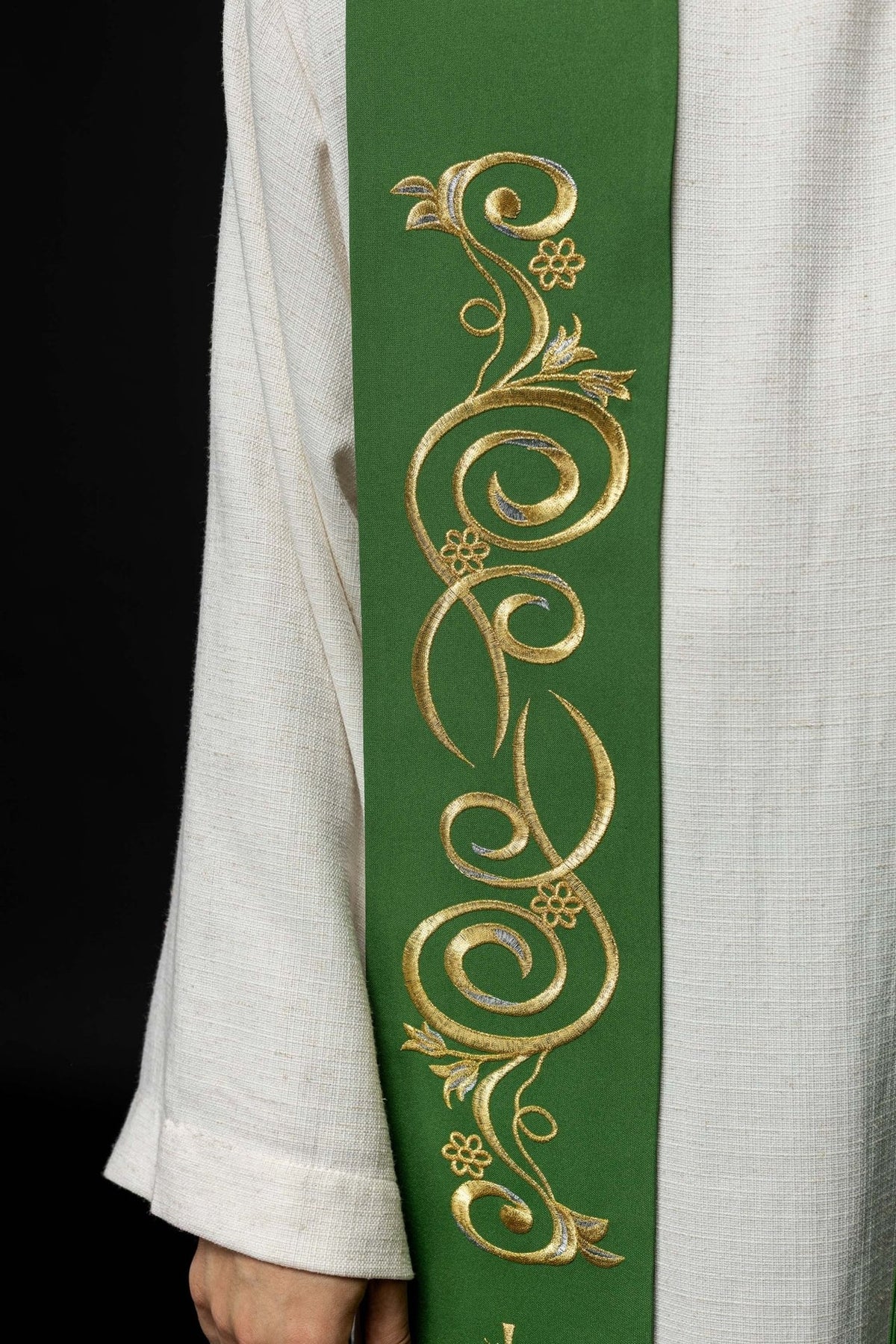 Green stole close-up showing embroidered gold scrollwork with floral details