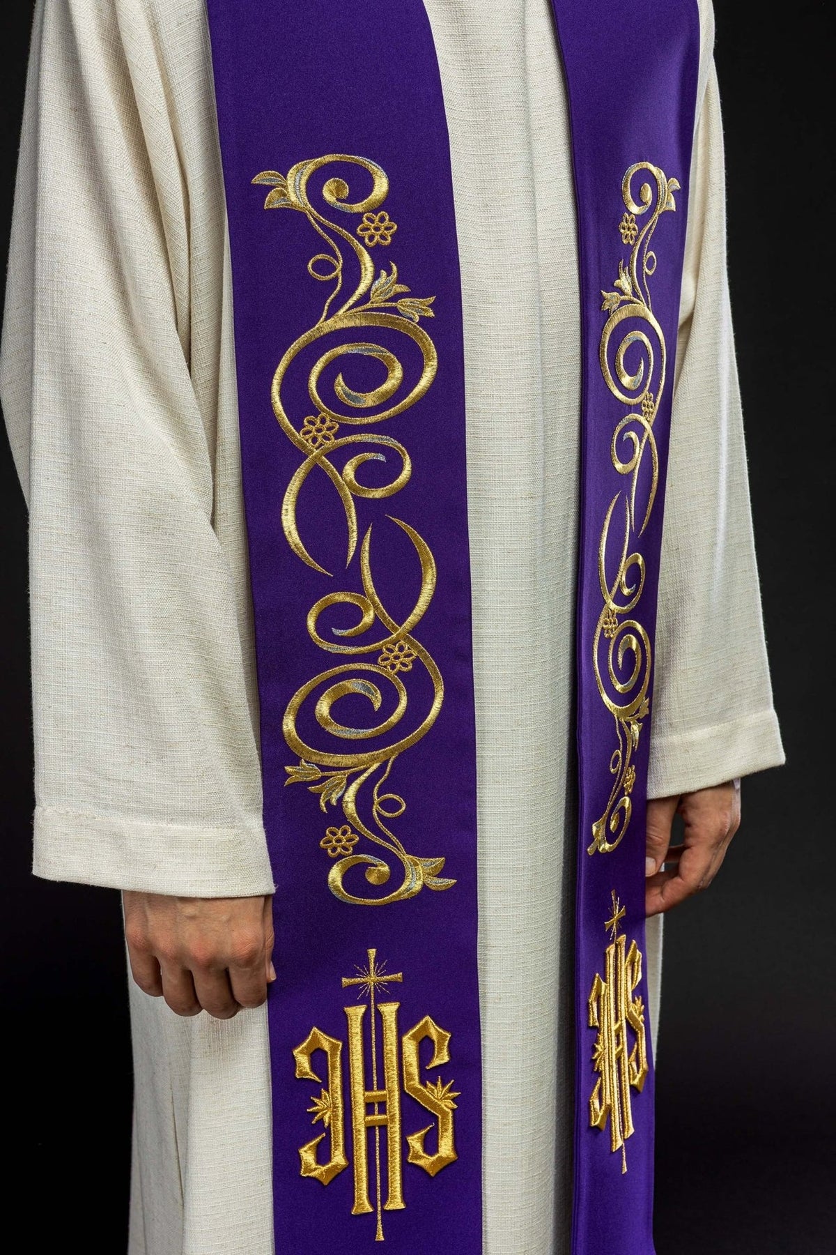 Purple stole close-up showing ornate gold scroll embroidery and IHS symbol