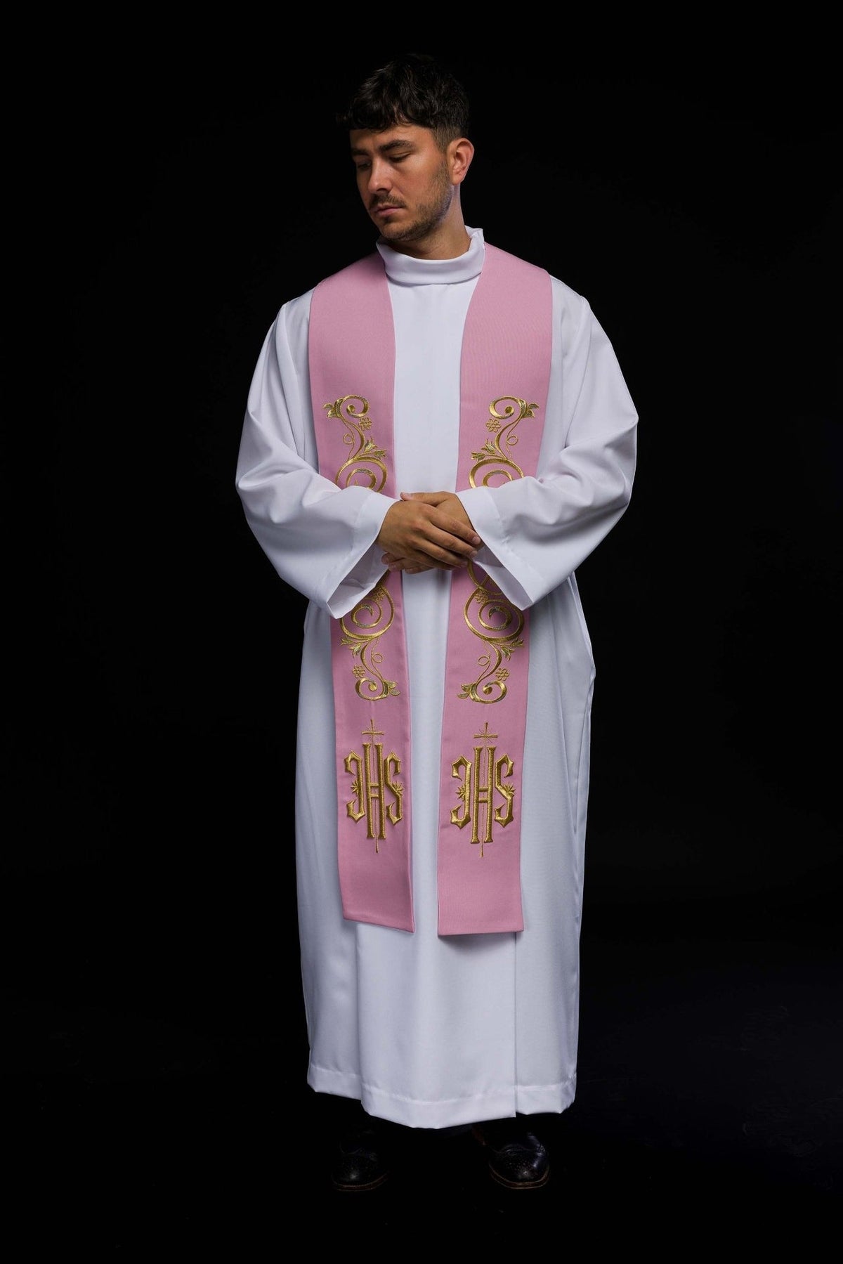 Pink embroidered stole worn in front view with gold scrollwork and IHS motifs