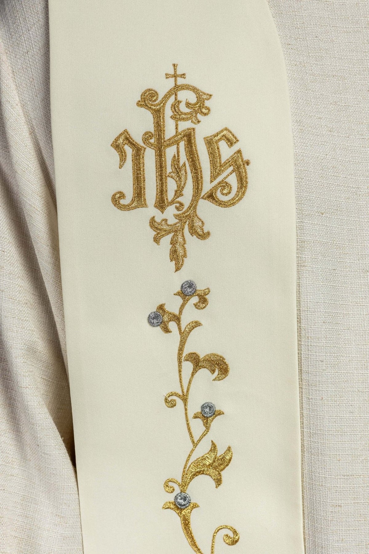 Stole close-up showing gold IHS embroidery on a cross and silver-accented floral motifs