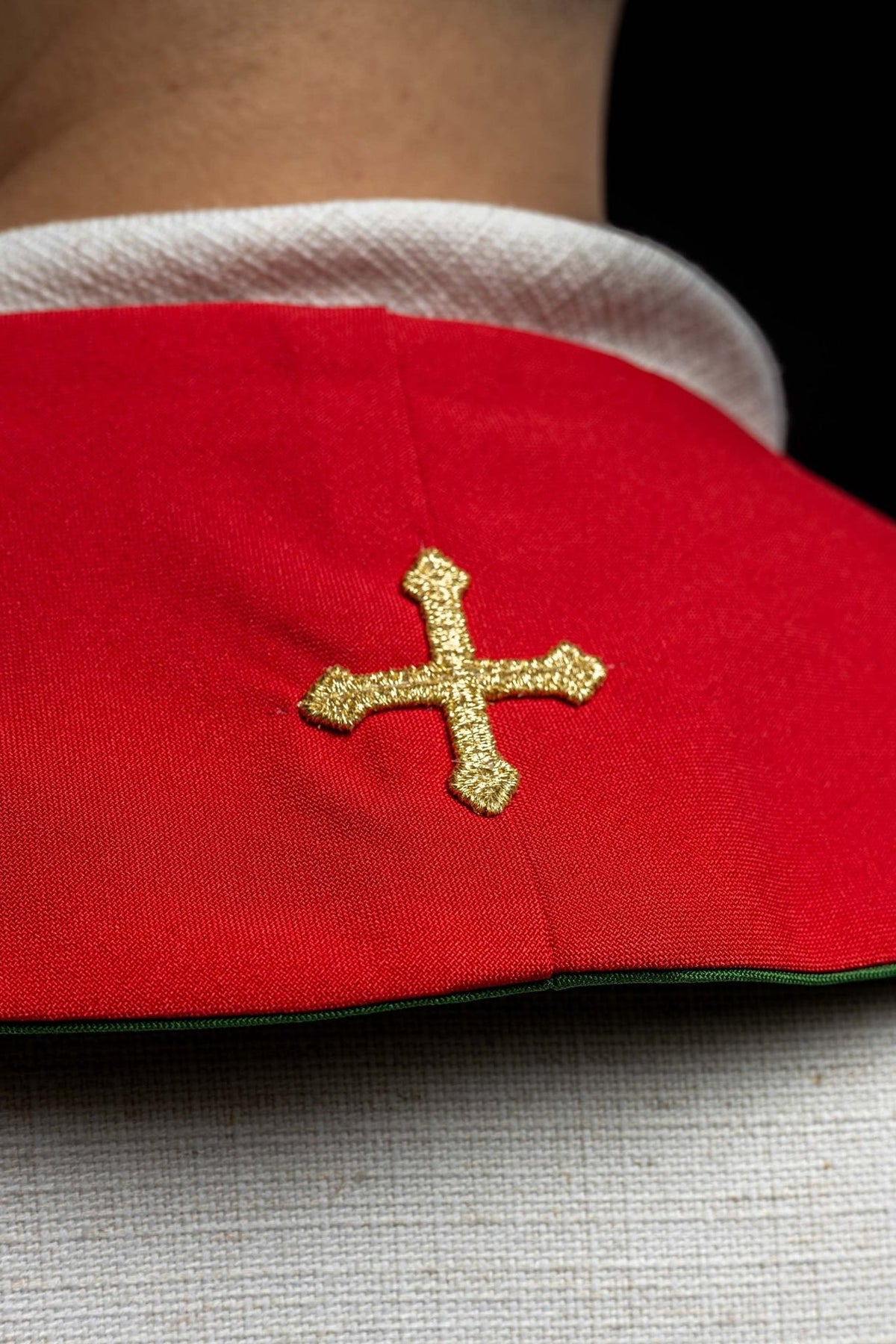 IHS stole close-up showing gold cross embroidery on red fabric