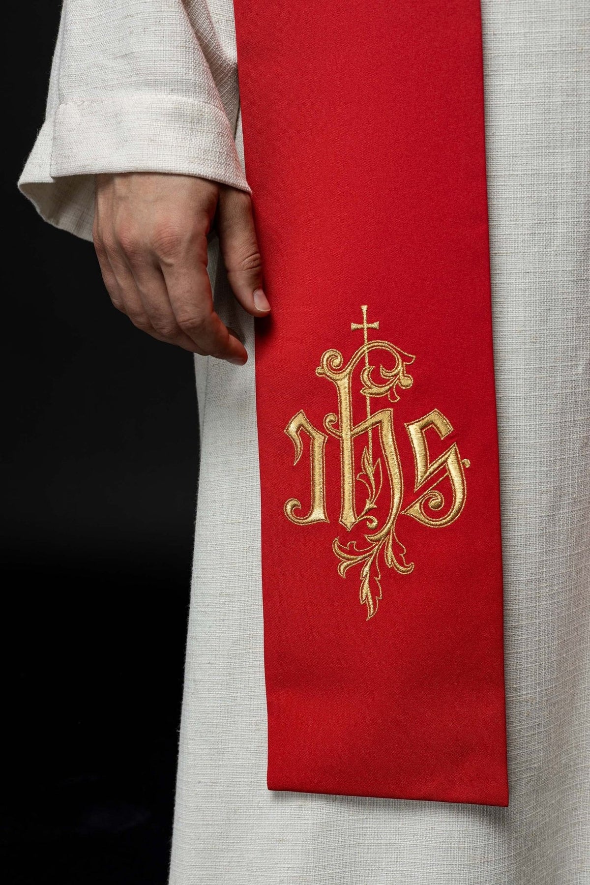 Red embroidered stole close-up showing gold IHS embroidery