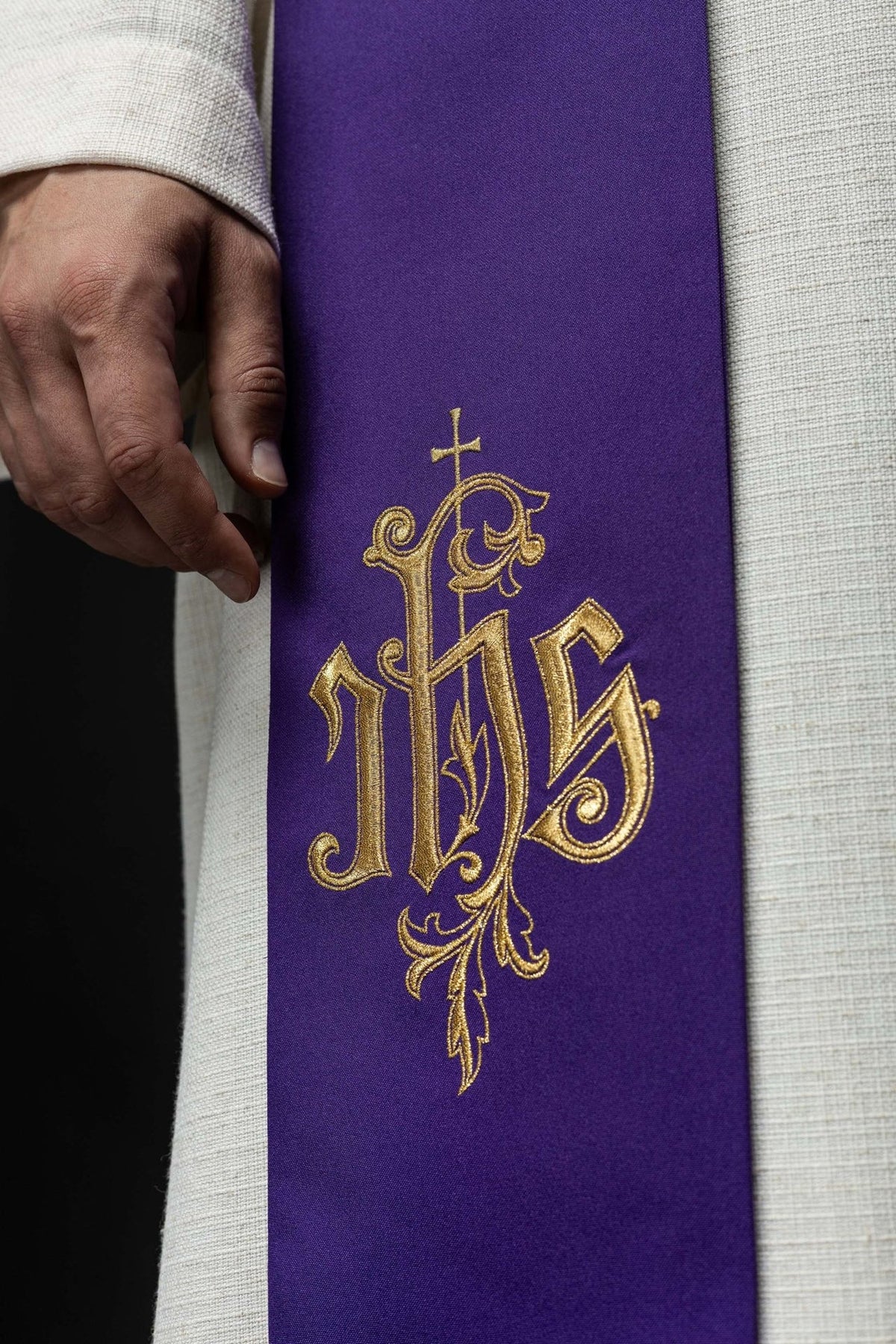 IHS stole close-up showing gold embroidered IHS motif on purple fabric