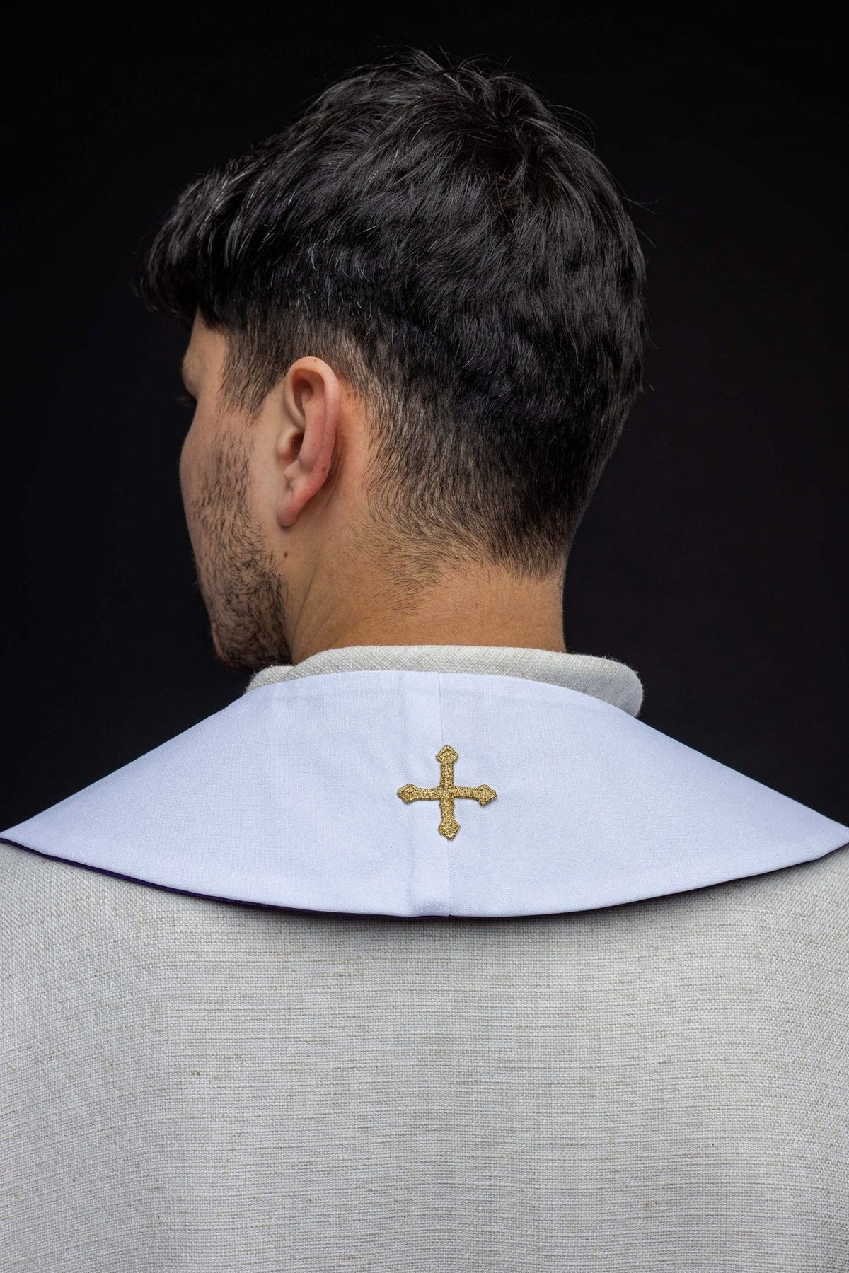 White stole worn from the back, with a small gold cross embroidery