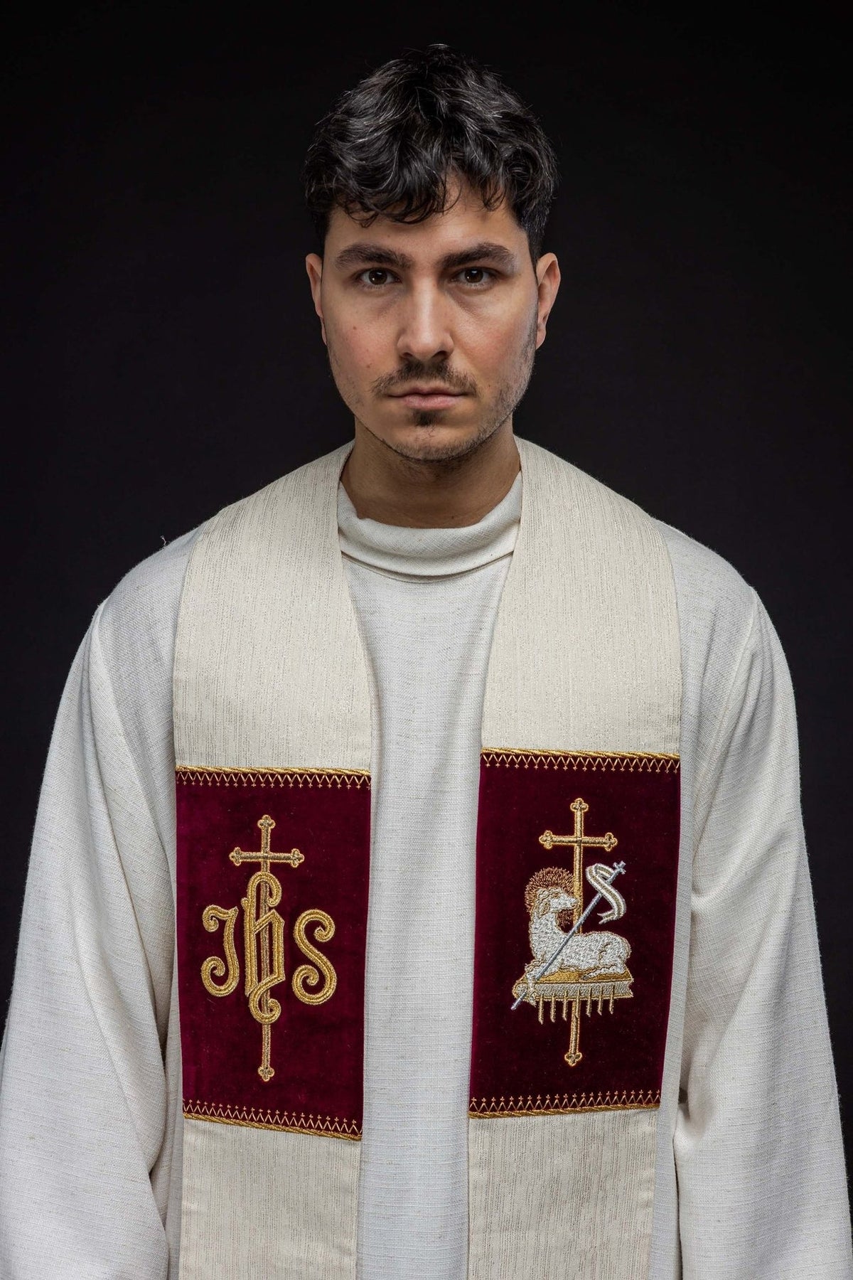Embroidered stole worn from the front, showing burgundy JHS and Agnus Dei panels
