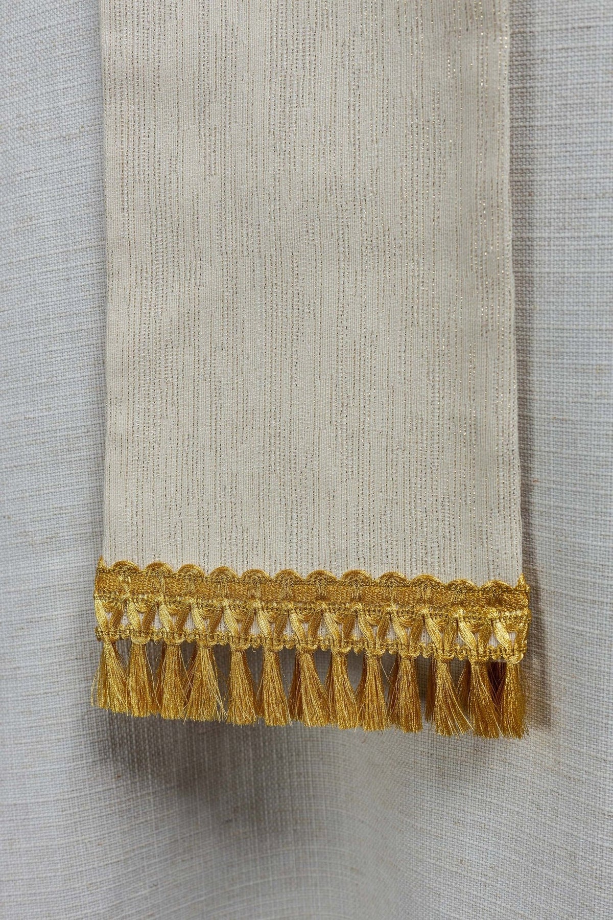 Ivory stole close-up showing vertical woven texture and gold tassel trim