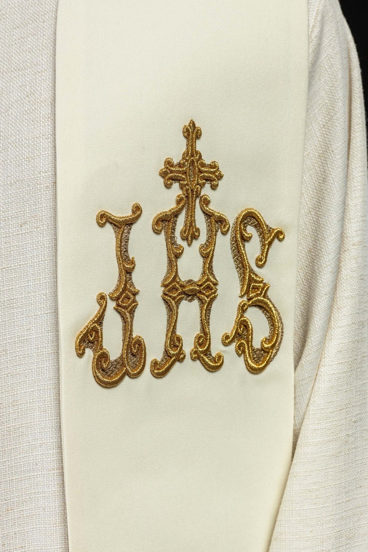 Priest stole close-up showing gold IHS and cross embroidery on ecru fabric