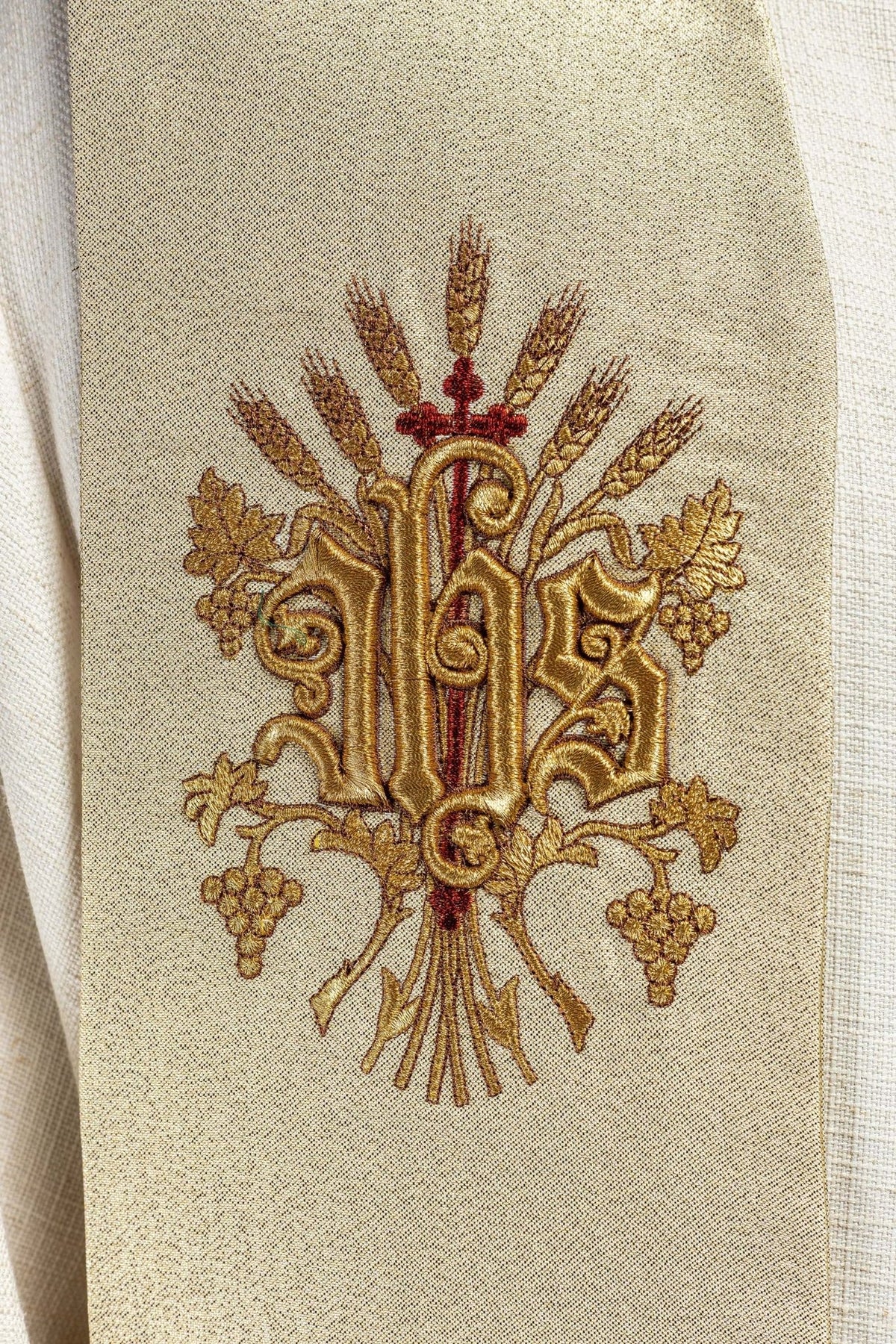 Gold stole close-up showing embroidered gold monogram with wheat and grape motifs
