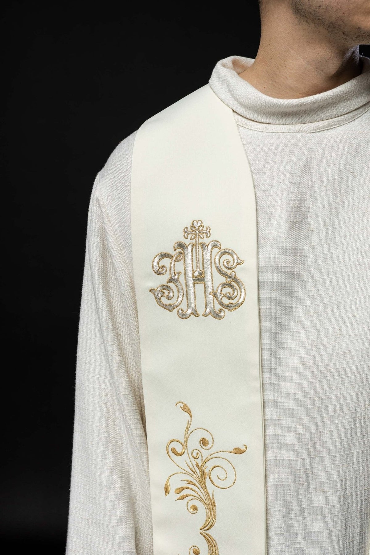 Ecru stole close-up with gold IHS embroidery and partial scroll motif