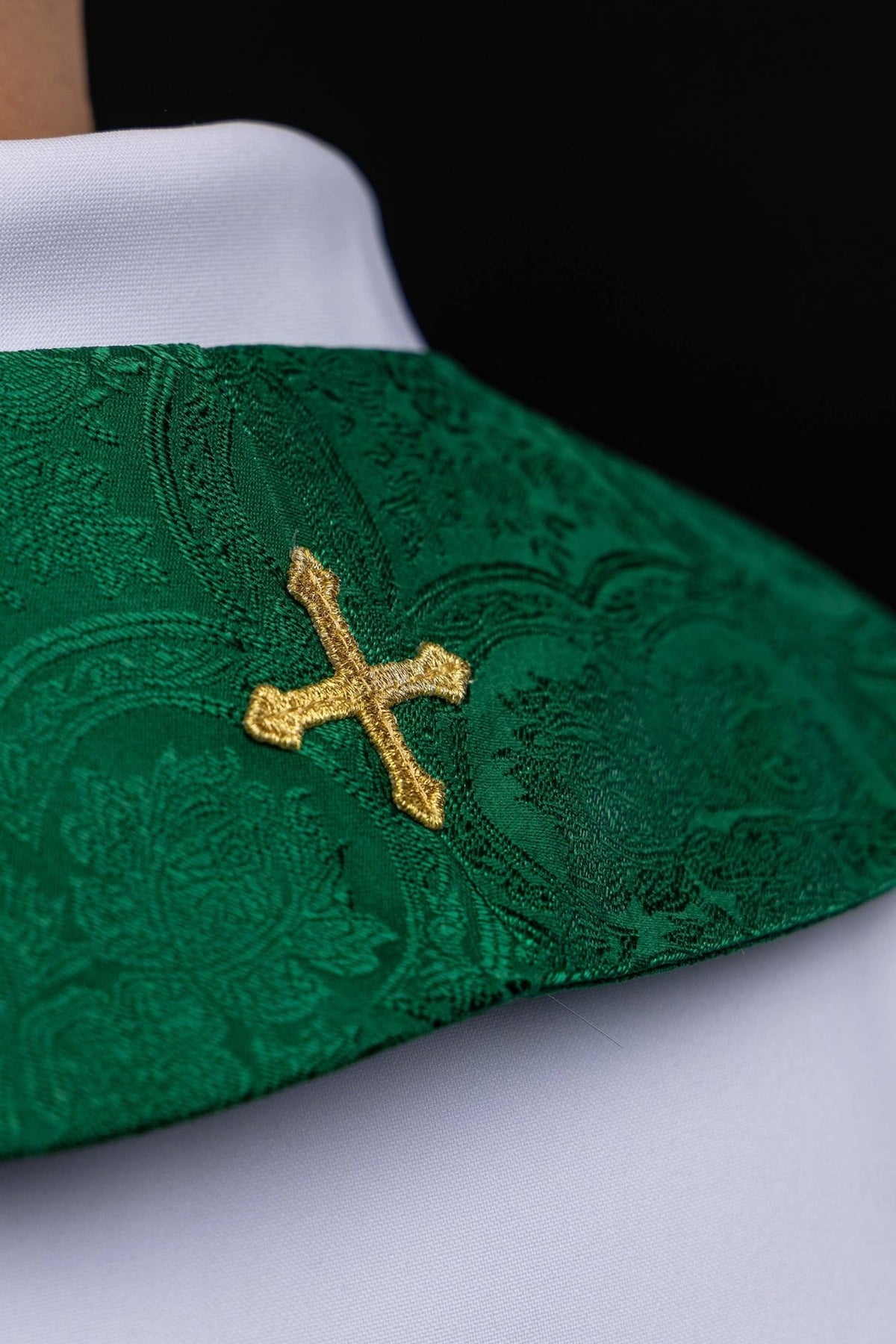 Green stole detail showing embroidered gold cross on jacquard fabric