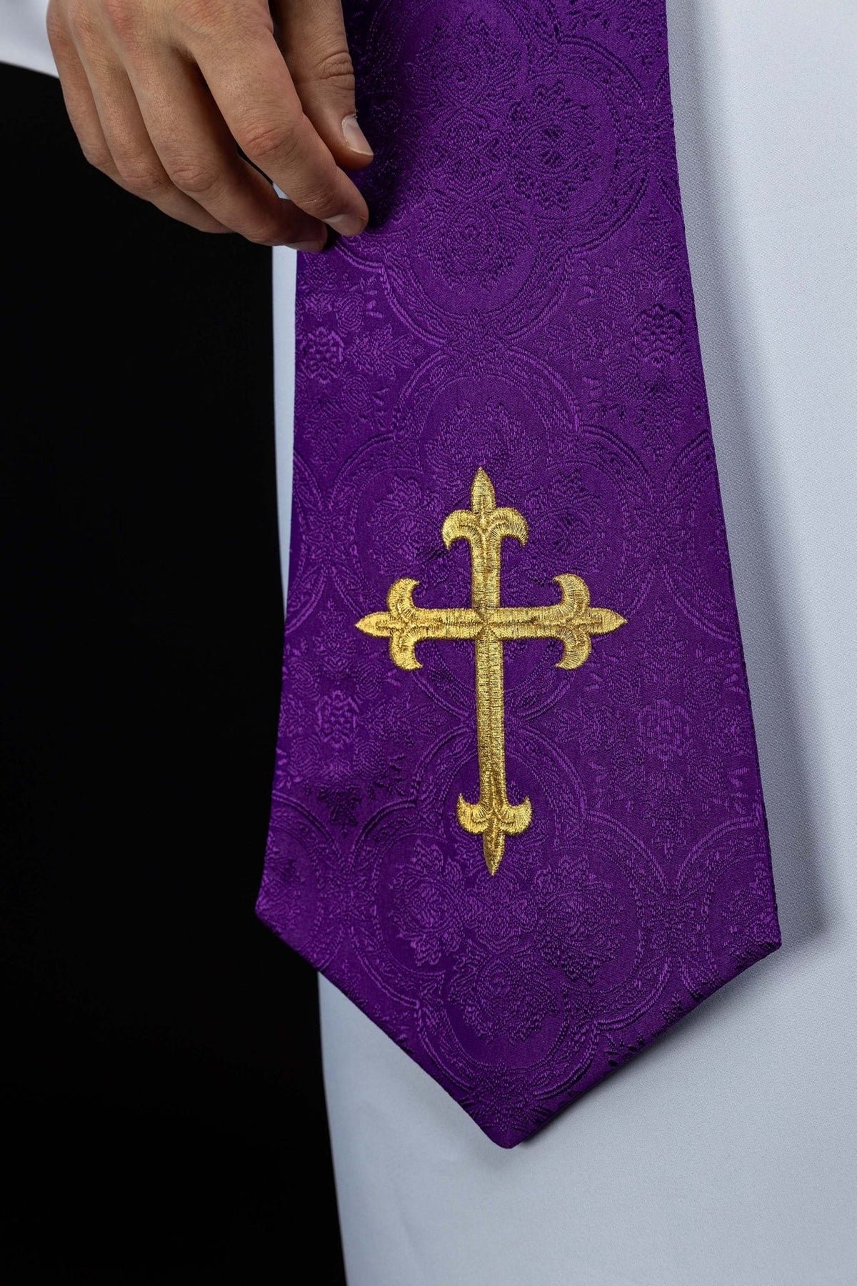 Purple priest stole close-up showing gold embroidered cross and jacquard fabric