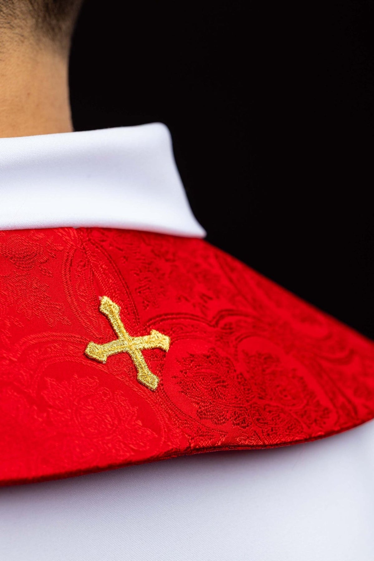 Red stole close-up showing gold cross embroidery on jacquard fabric