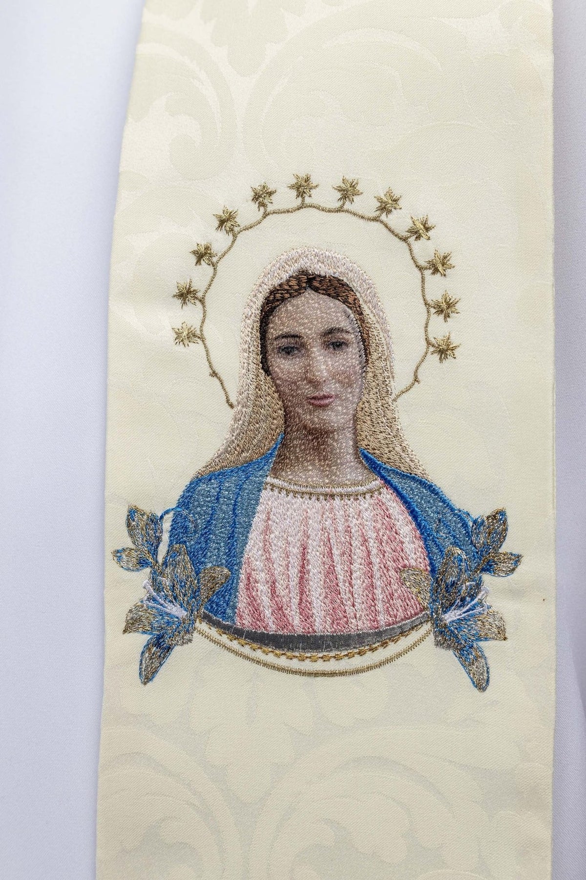 Stole close-up of embroidered Our Lady image with blue mantle, pink robe and gold halo