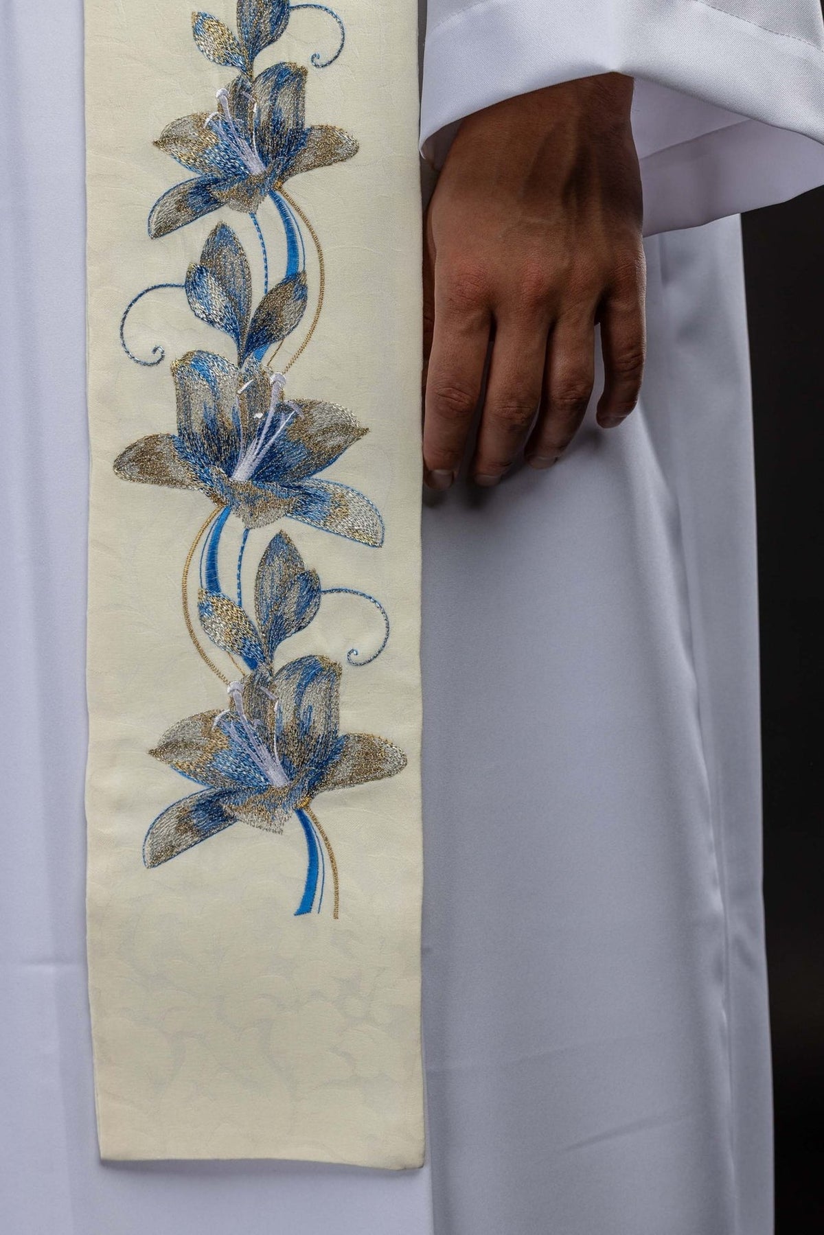 Stole close-up showing blue and gold embroidered floral motifs on ecru fabric