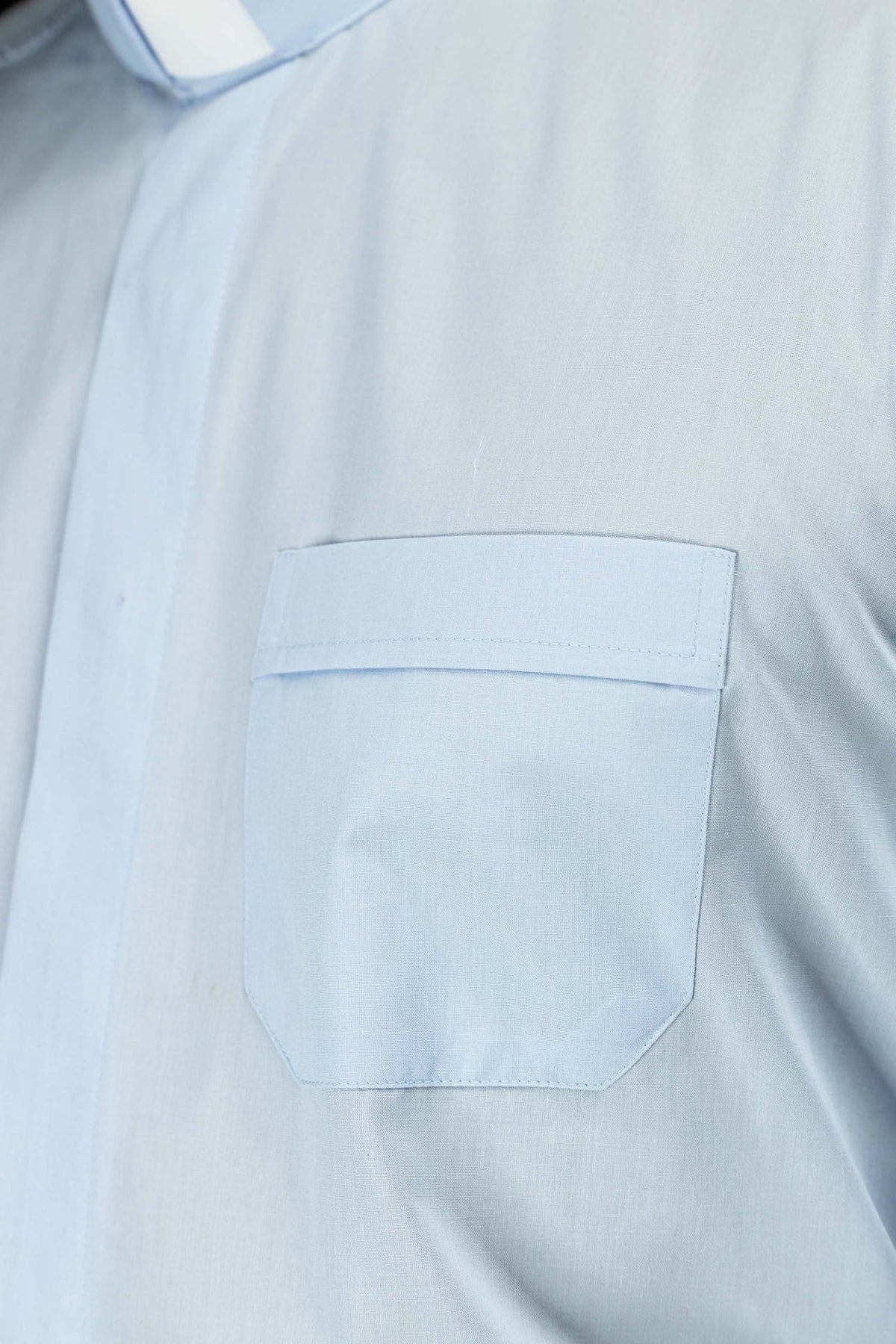 Light blue clergy shirt close-up showing chest pocket with flap