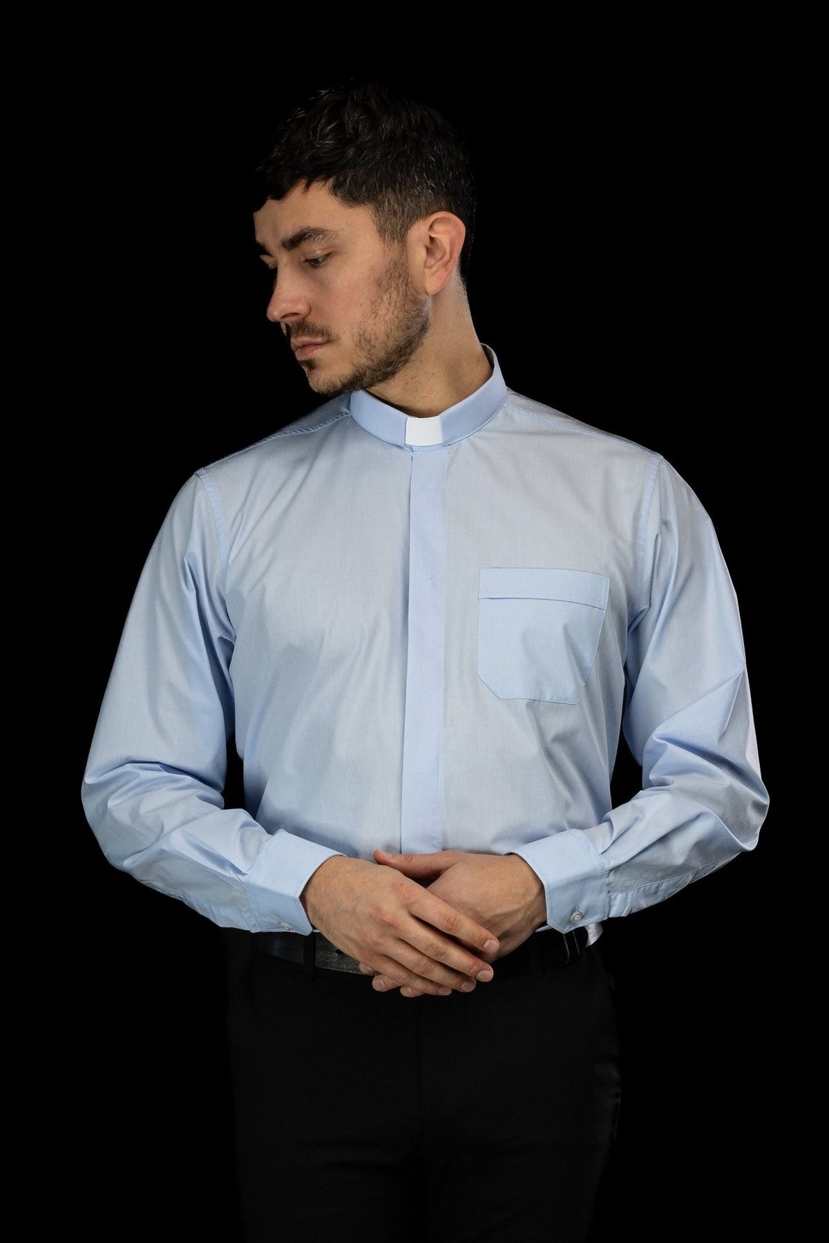 Light blue clergy shirt front view with folded arms and buttoned cuffs