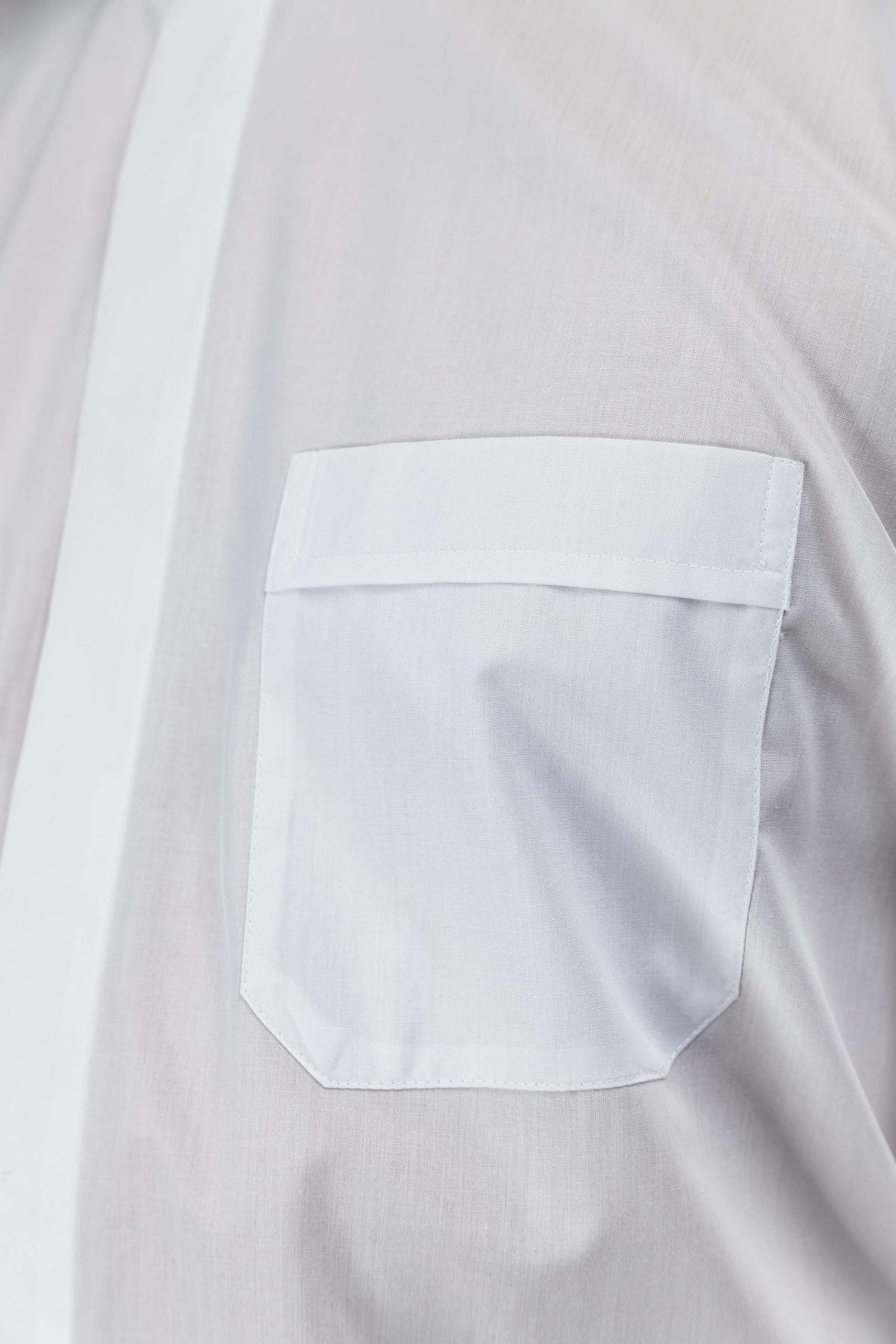 White clergy shirt close-up showing the chest pocket with flap