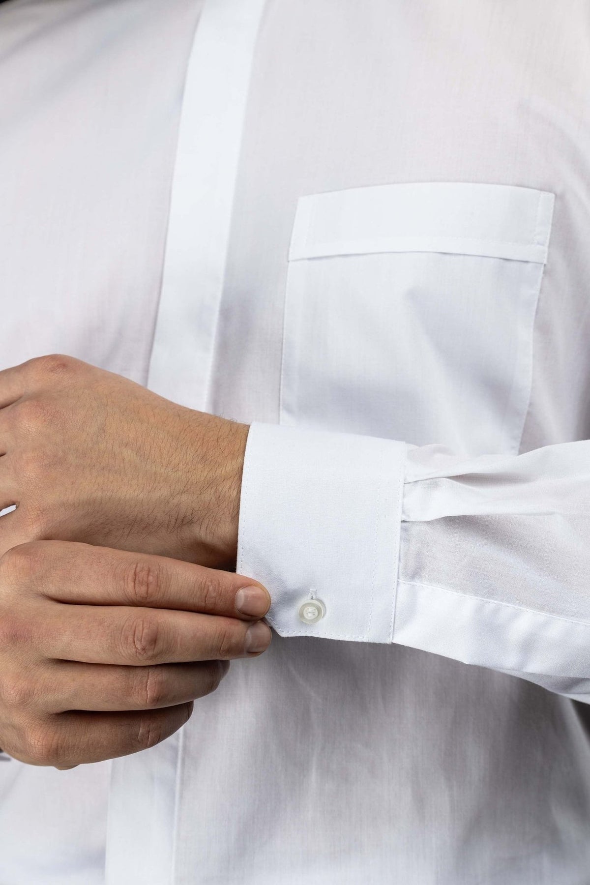 White clergy shirt close-up showing the chest pocket and long sleeve cuff