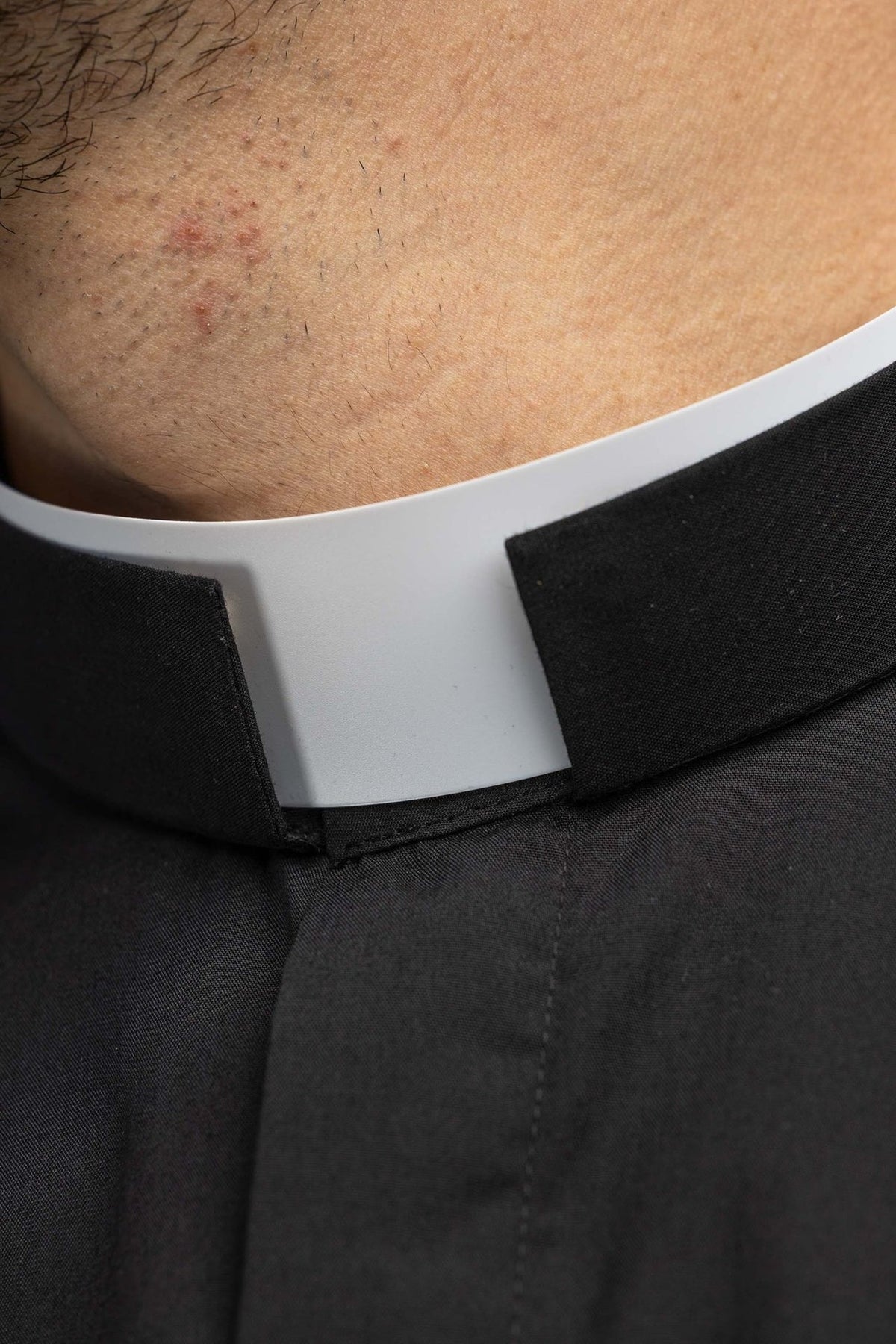 Black clergy shirt close-up showing the white clerical collar