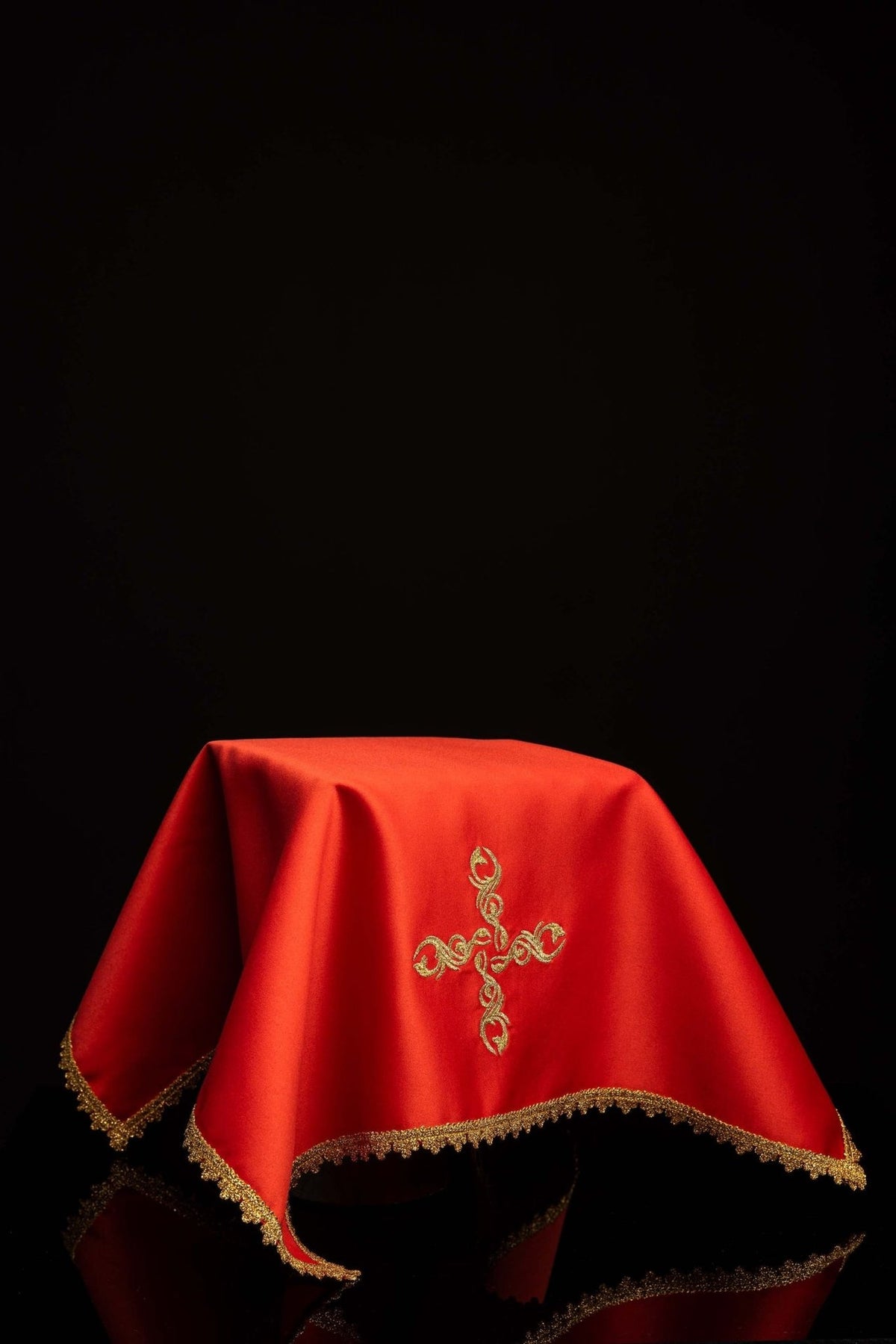 Red chalice veil worn, with gold embroidered cross and gold trim