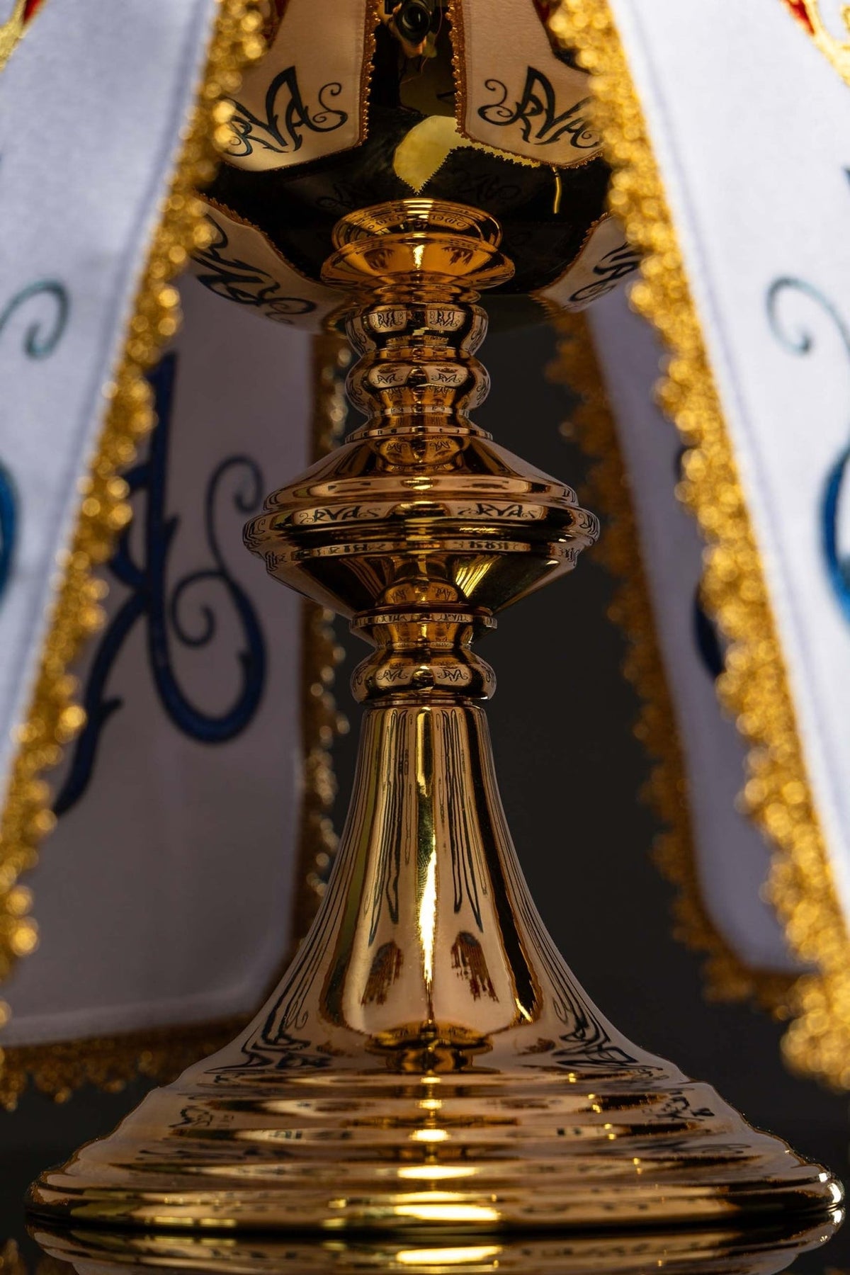 Ciborium veil viewed around a ciborium, showing white panels and Marian motif embroidery