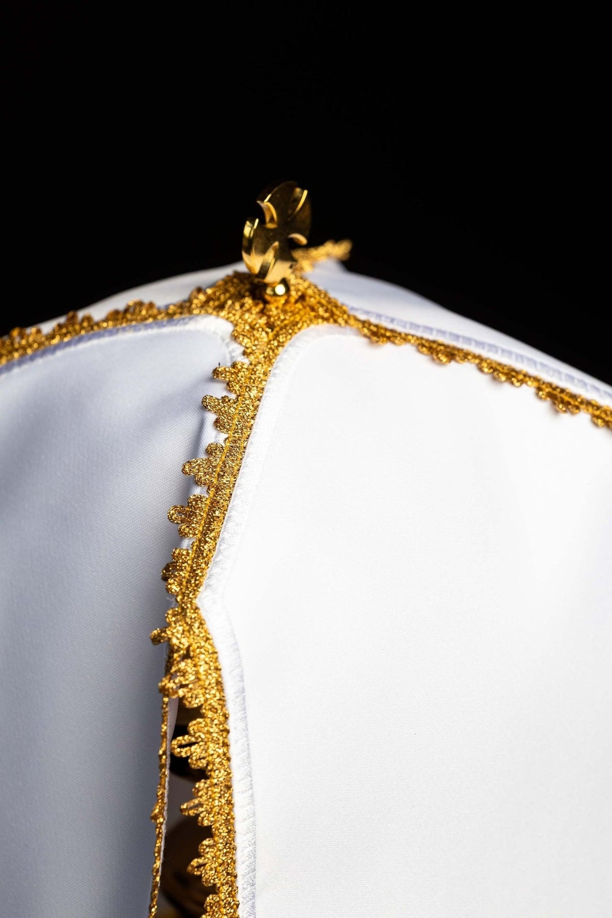 Ciborium veil close-up of white fabric, gold scalloped embroidery trim and top cross fitting