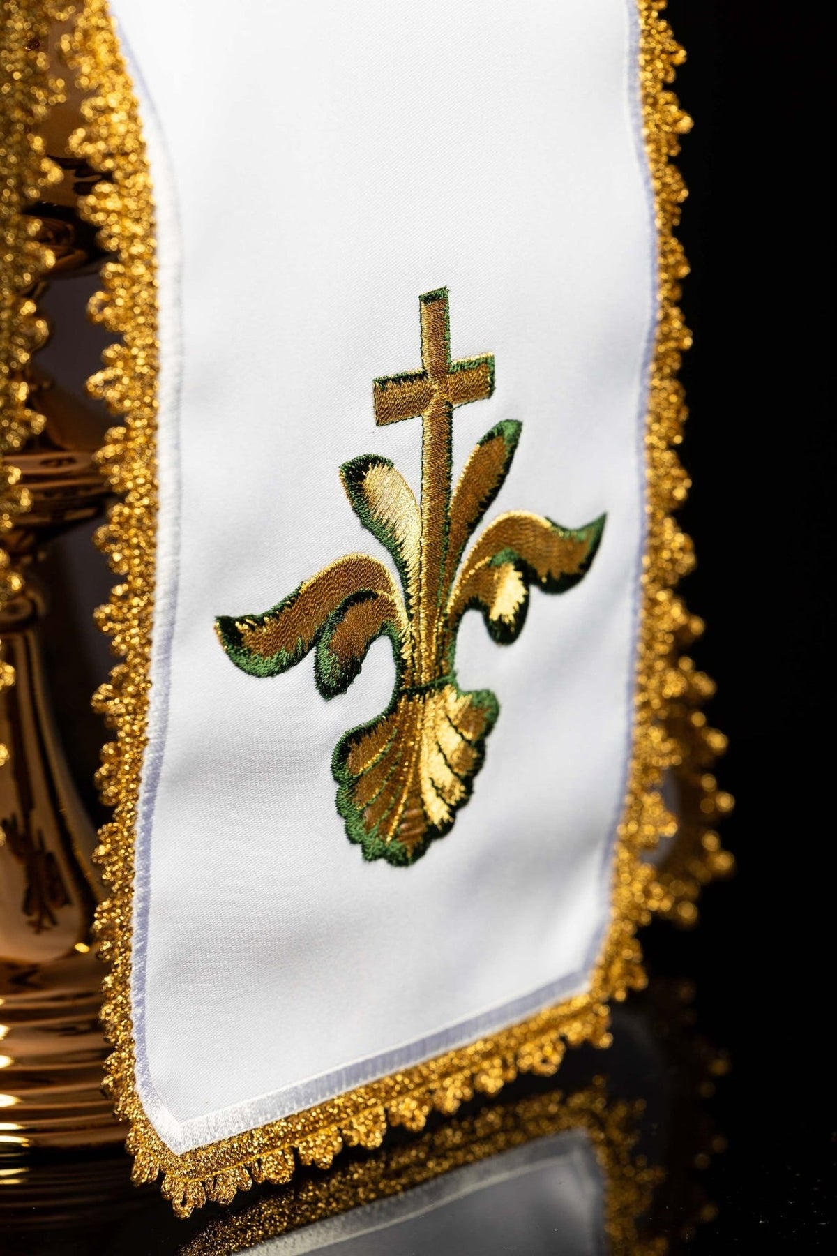 Ciborium veil close-up showing gold-and-green cross embroidery on white fabric