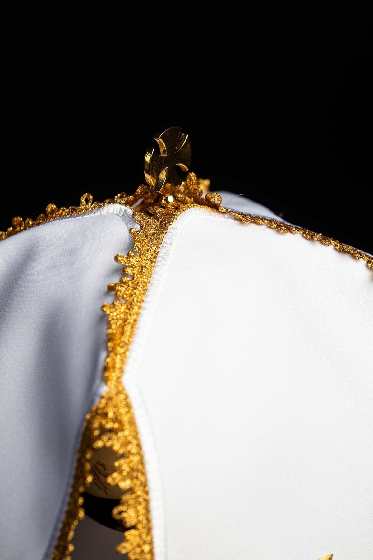 Ciborium veil detail showing white fabric, gold trim and top cross