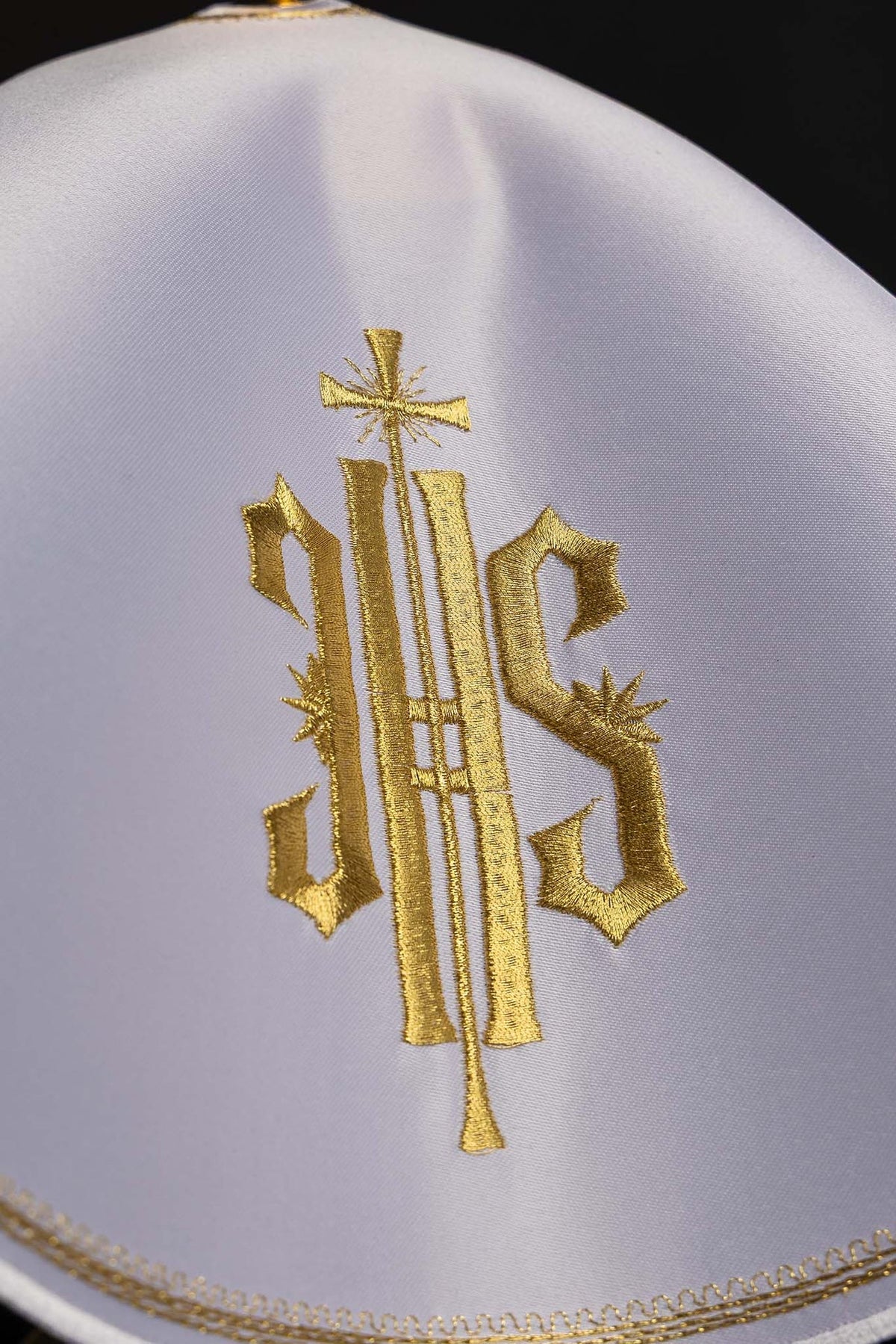 Ciborium veil close-up showing white fabric and gold IHS embroidery