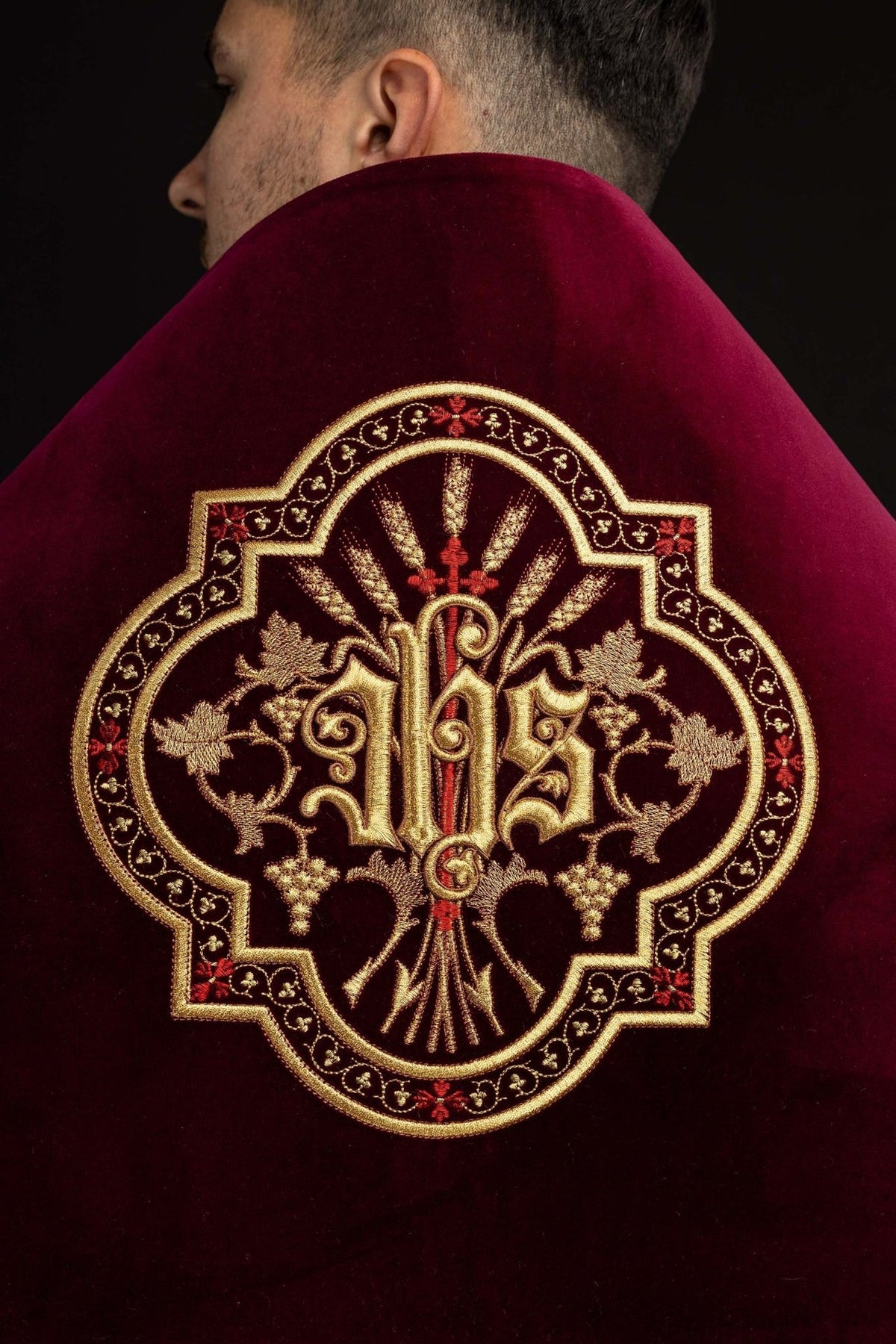 Humeral veil close-up of burgundy velvet with ornate gold IHS embroidery