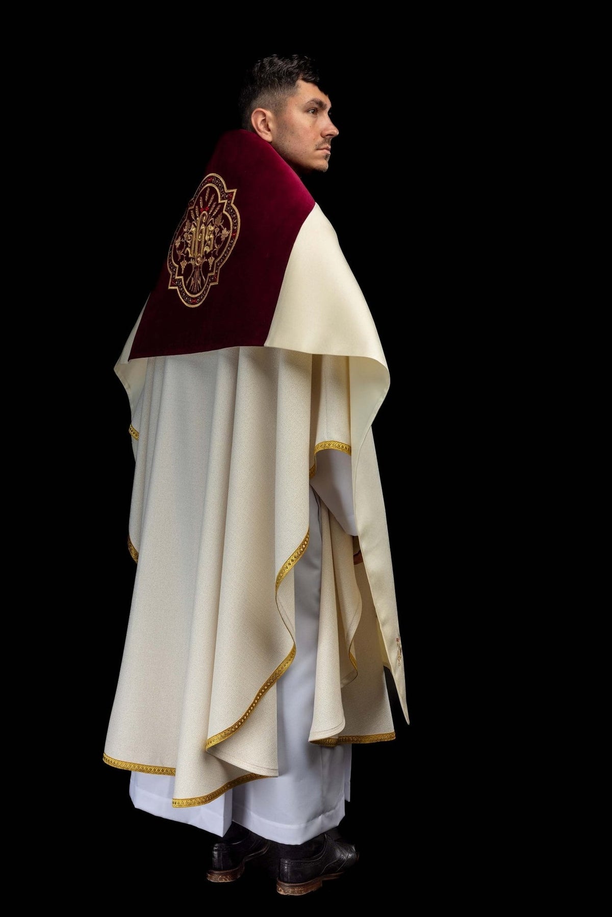 Humeral veil worn at a side angle, showing burgundy velvet panel with gold IHS embroidery