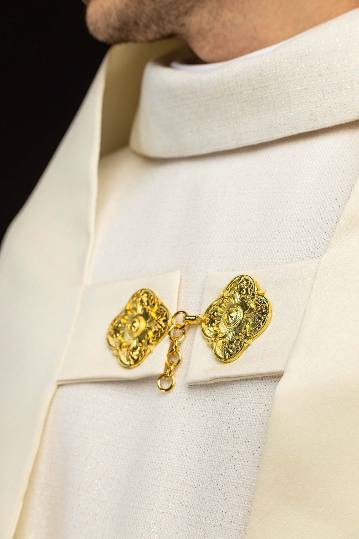 Humeral veil close-up showing ecru fabric, collar fastening and gold clasp