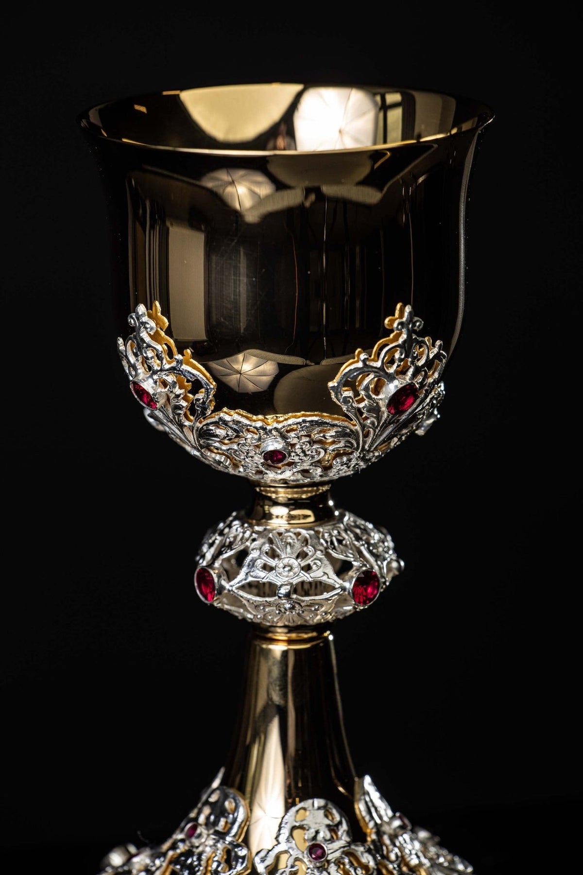 Gold-plated chalice close-up of decorative base with silver scrollwork and red rubies