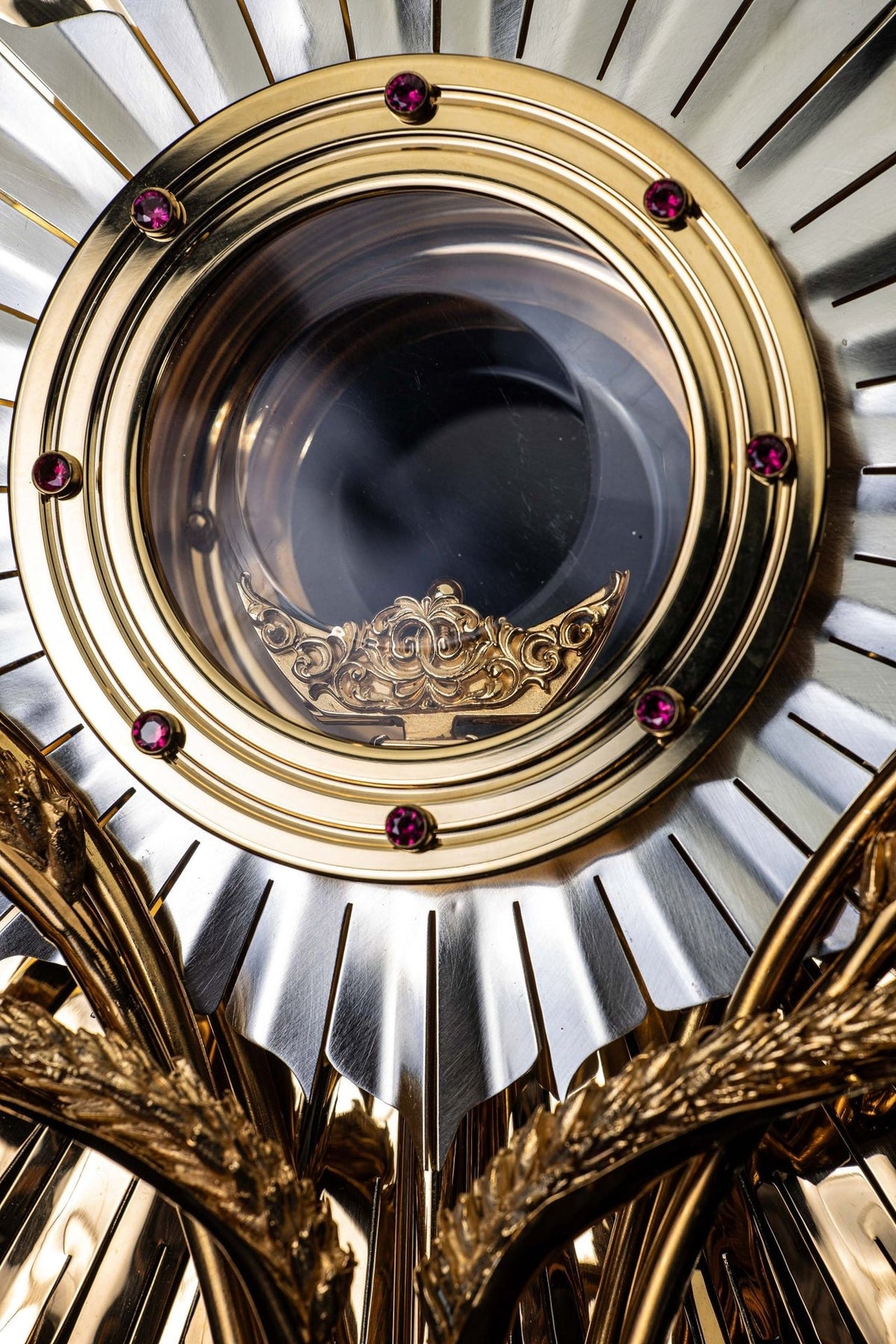 Gold-plated brass monstrance close-up showing the ruby-set circular frame and silver-toned rays