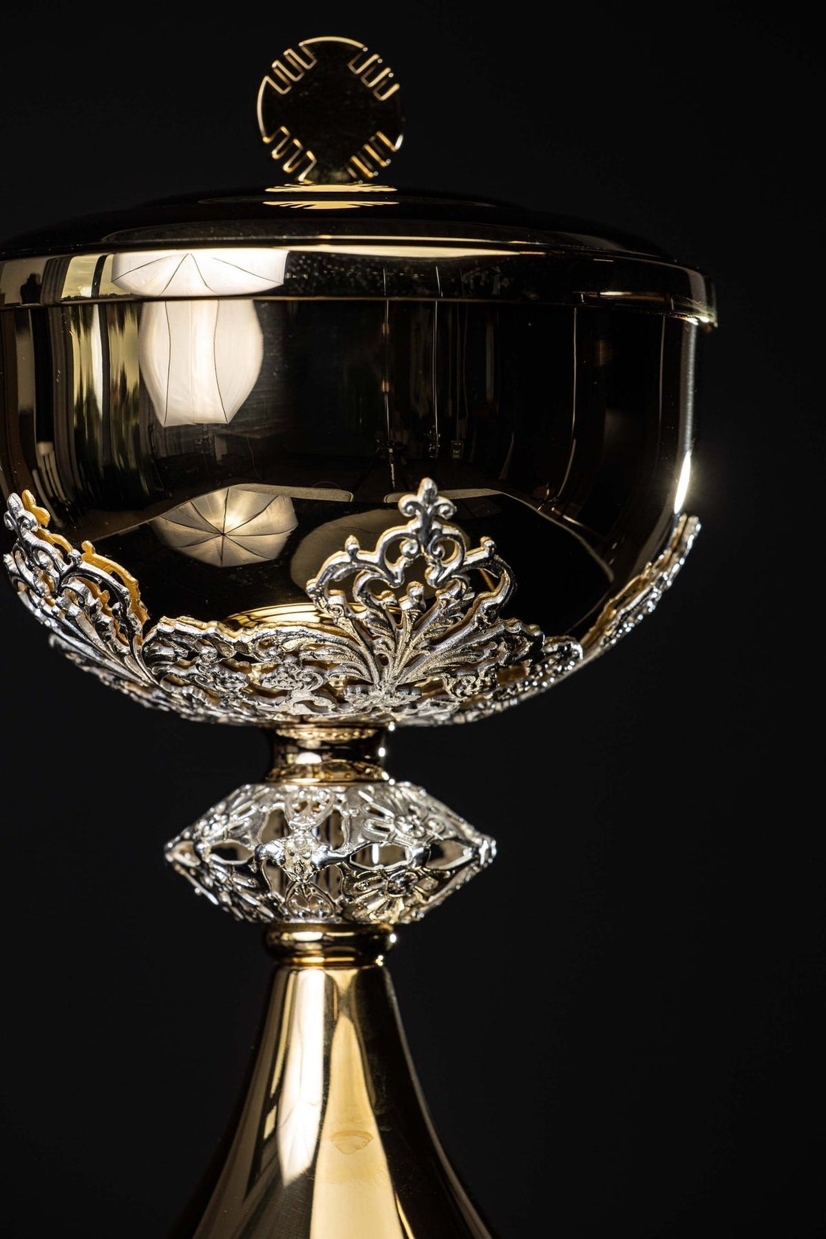 Ciborium close-up showing silver floral decorations around the gold bowl
