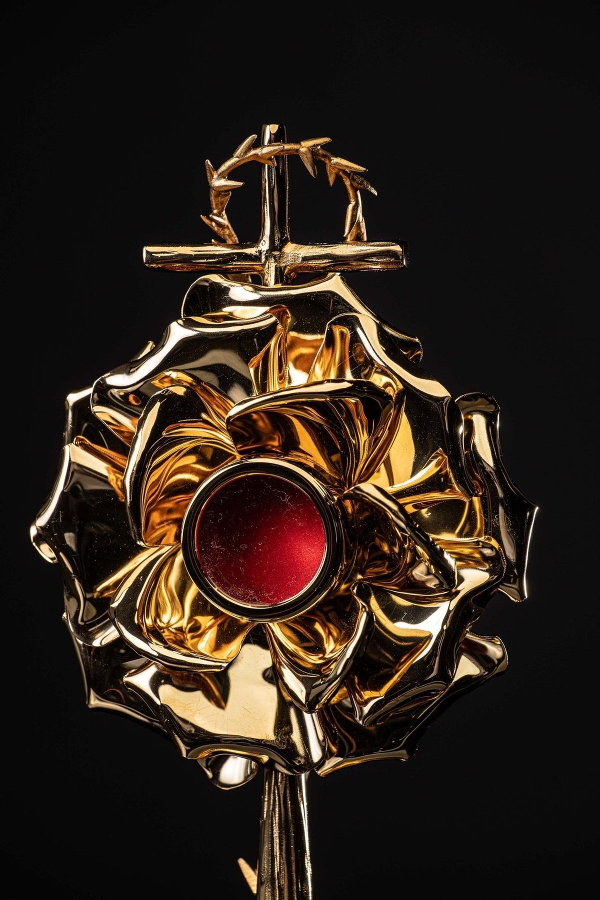Gilded brass reliquary close-up showing red center, cross, and crown of thorns