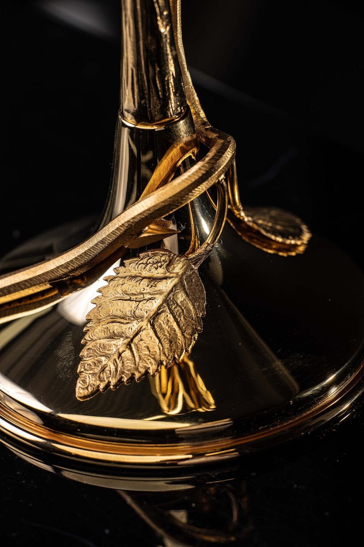 Gilded brass reliquary base close-up with textured leaf ornament and curved detail