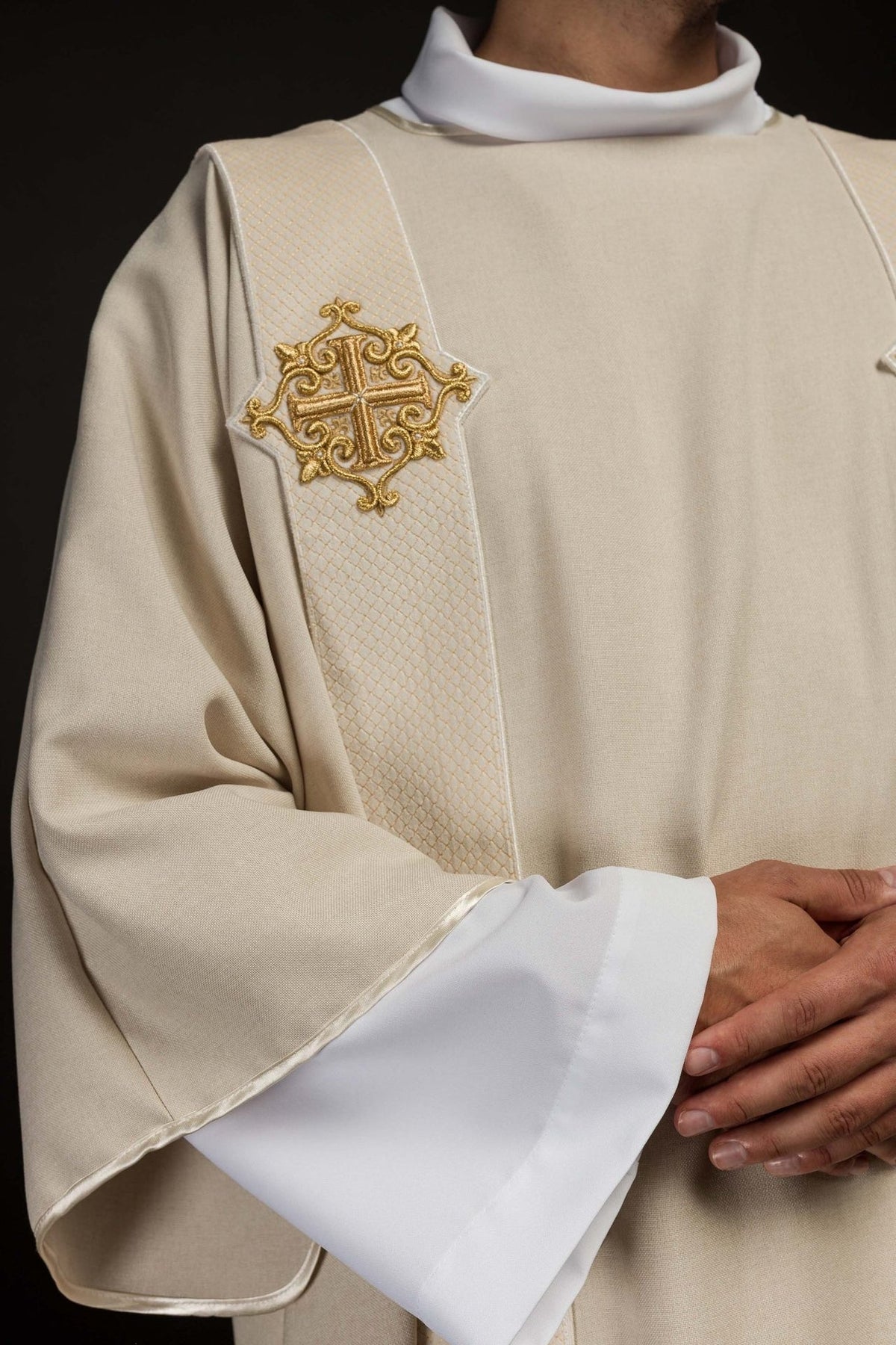 Ecru dalmatic close-up showing quilted orphrey and gold embroidered cross