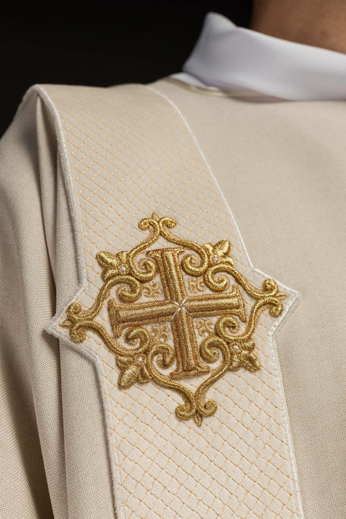 Ecru dalmatic detail showing gold cross embroidery and satin sleeve trim