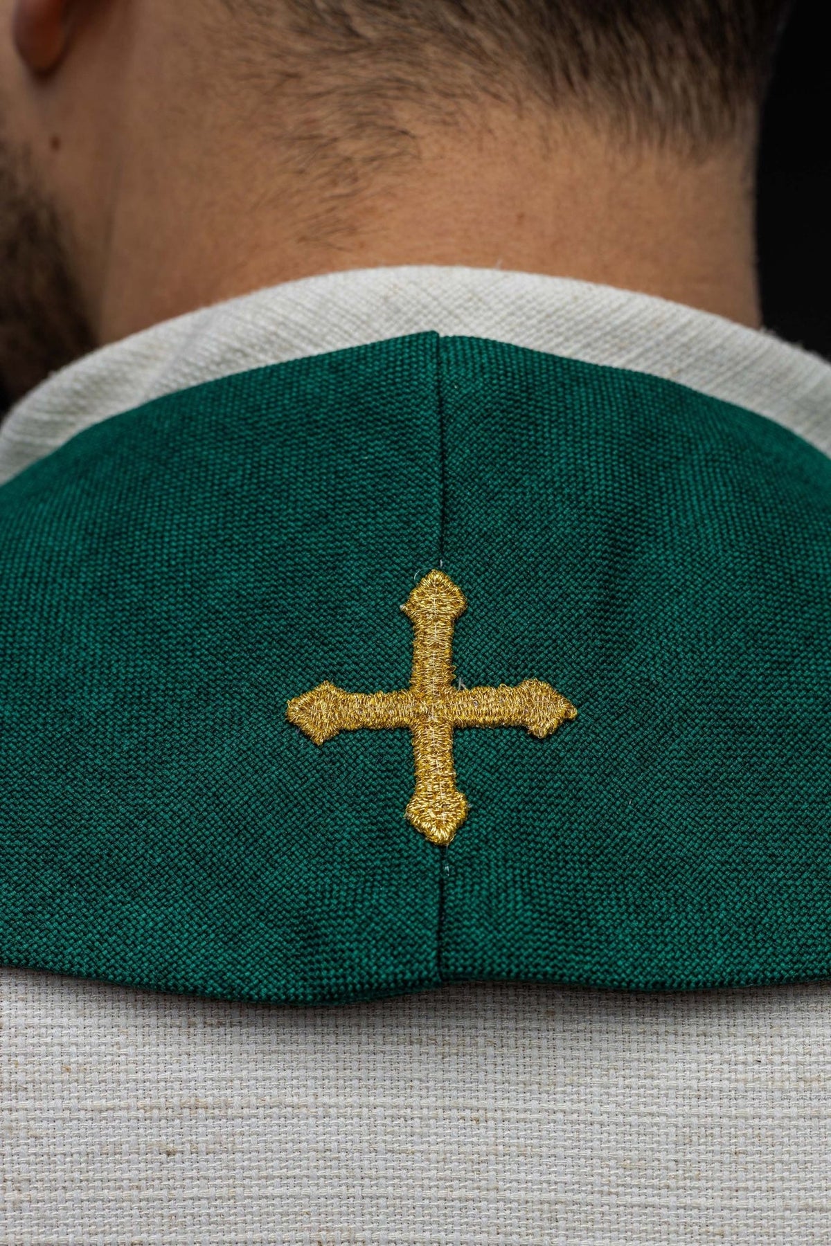 Green velvet stole close-up showing gold embroidered cross at the neck