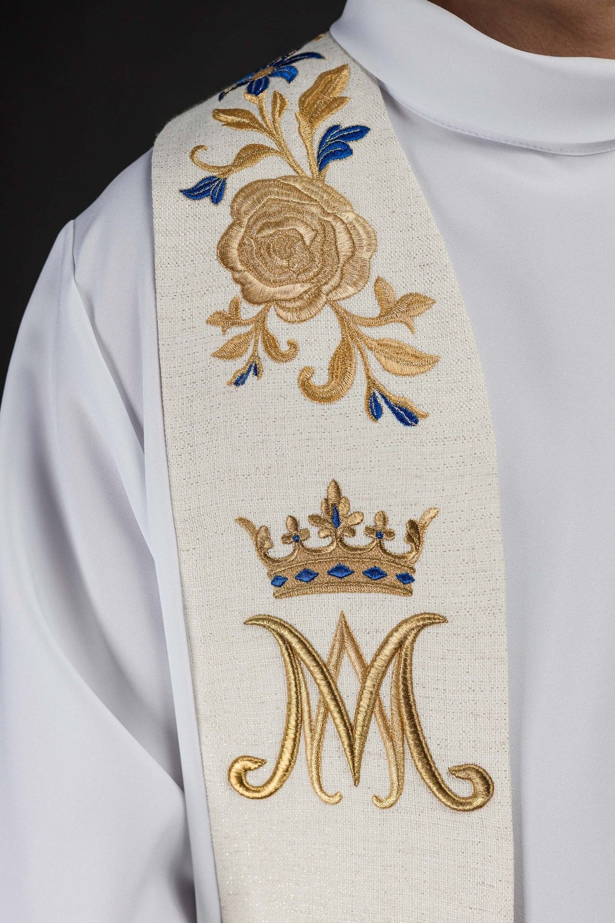 Embroidered stole detail showing gold rose embroidery and crowned Marian symbol
