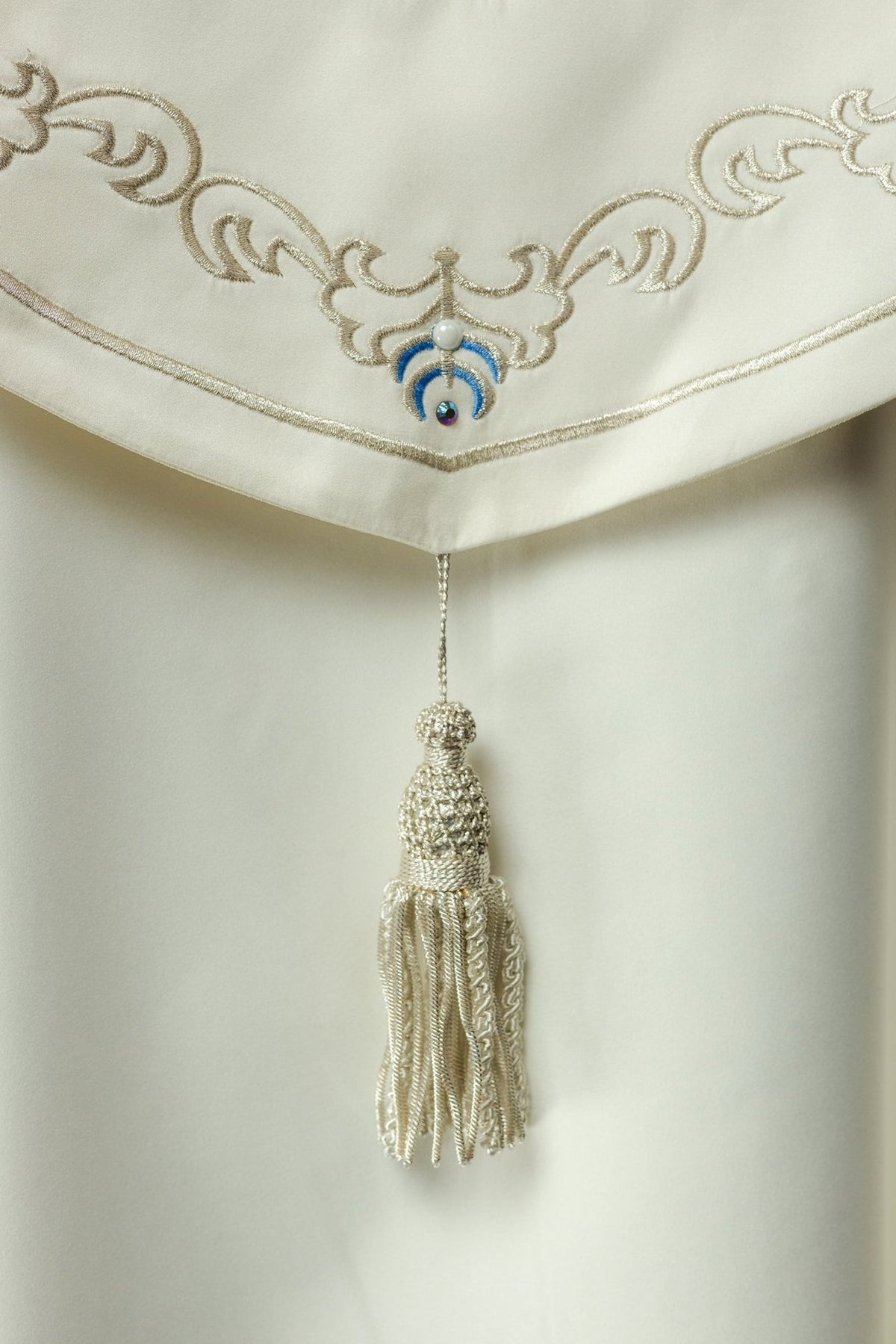 Cope close-up showing ivory satin, gold embroidery, blue motifs and tassel